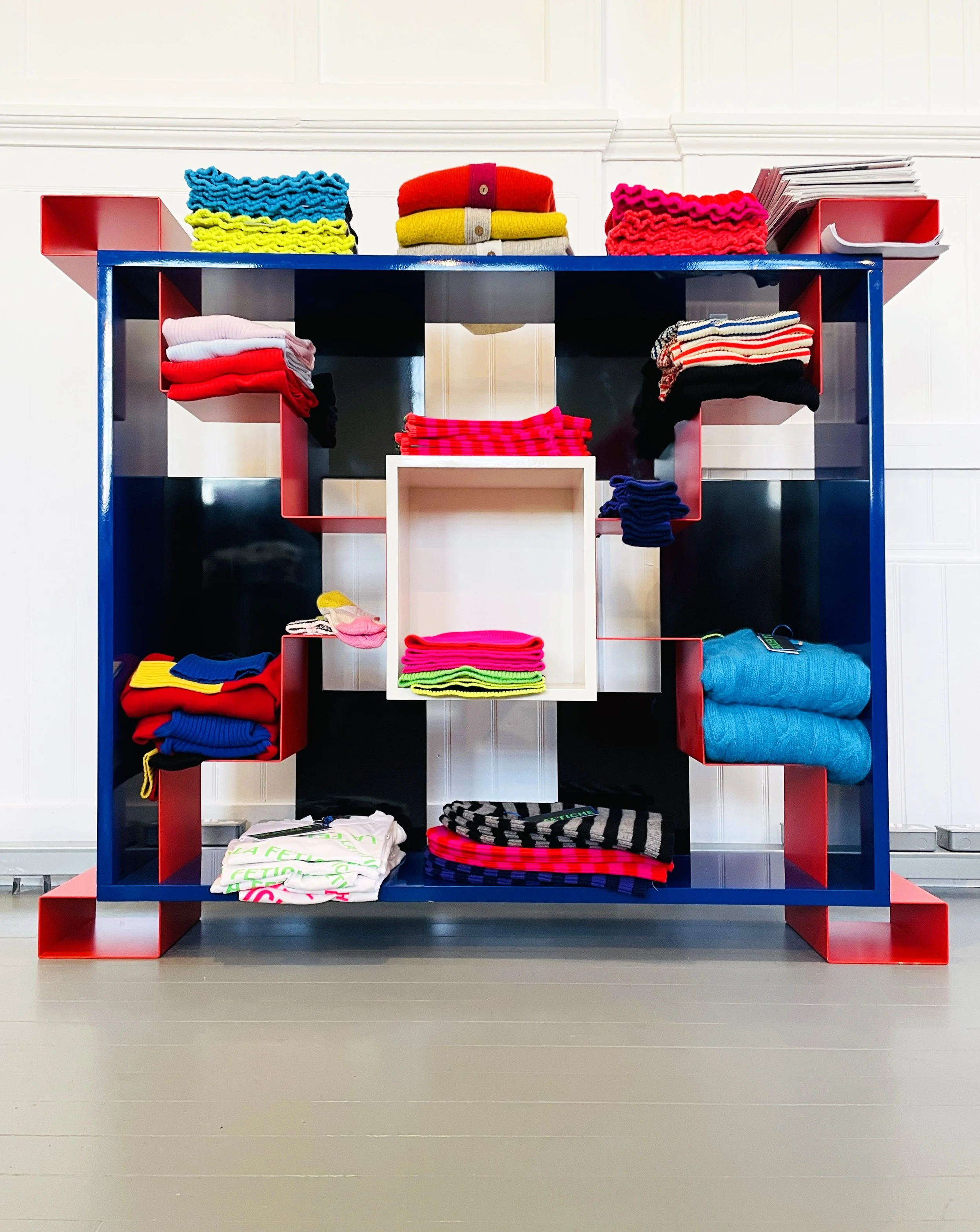 Display shelf with folded colorful clothes and fabrics arranged in a geometric pattern.