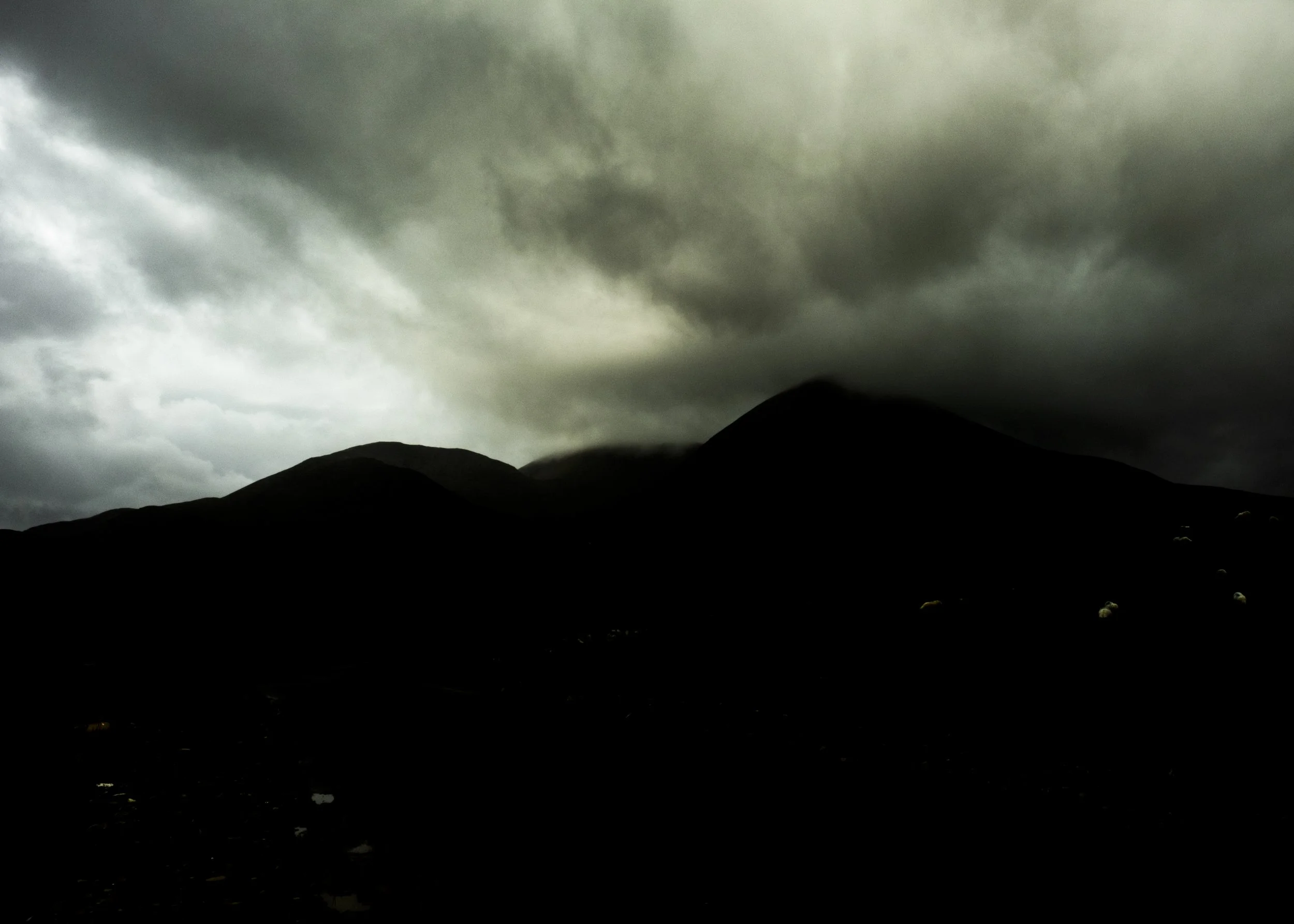Dark, stormy clouds over mountain silhouettes at dusk or dawn.