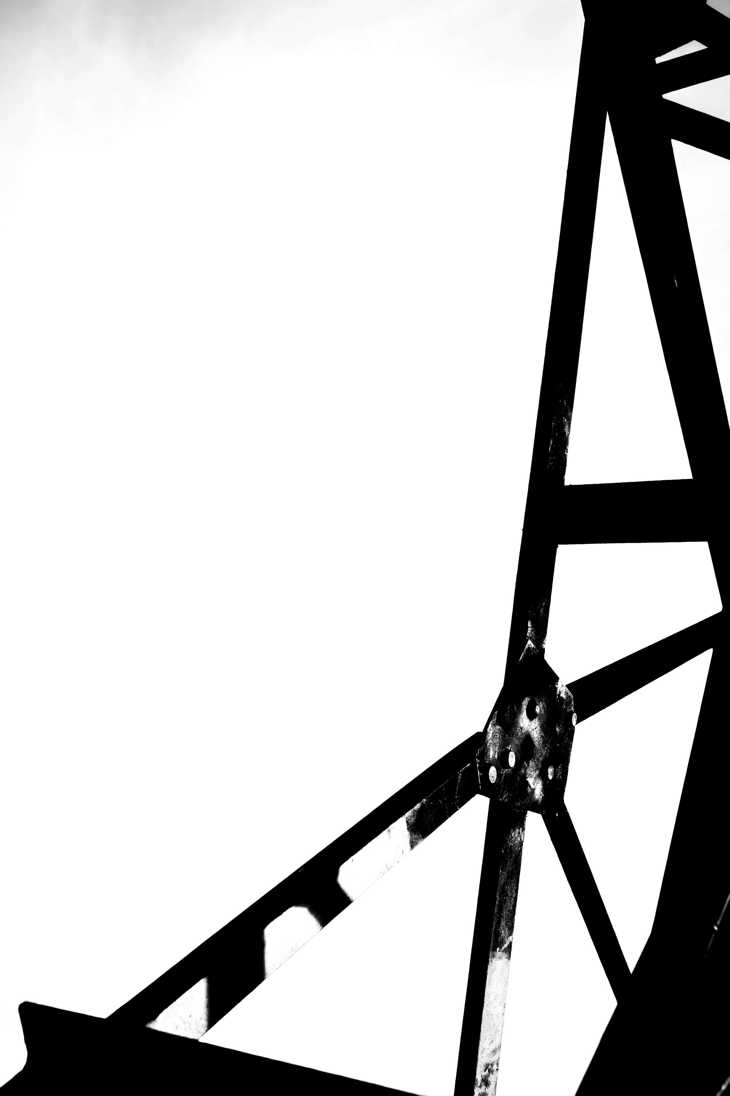Silhouette of a metallic bridge or framework with geometric lines and angles in black and white.
