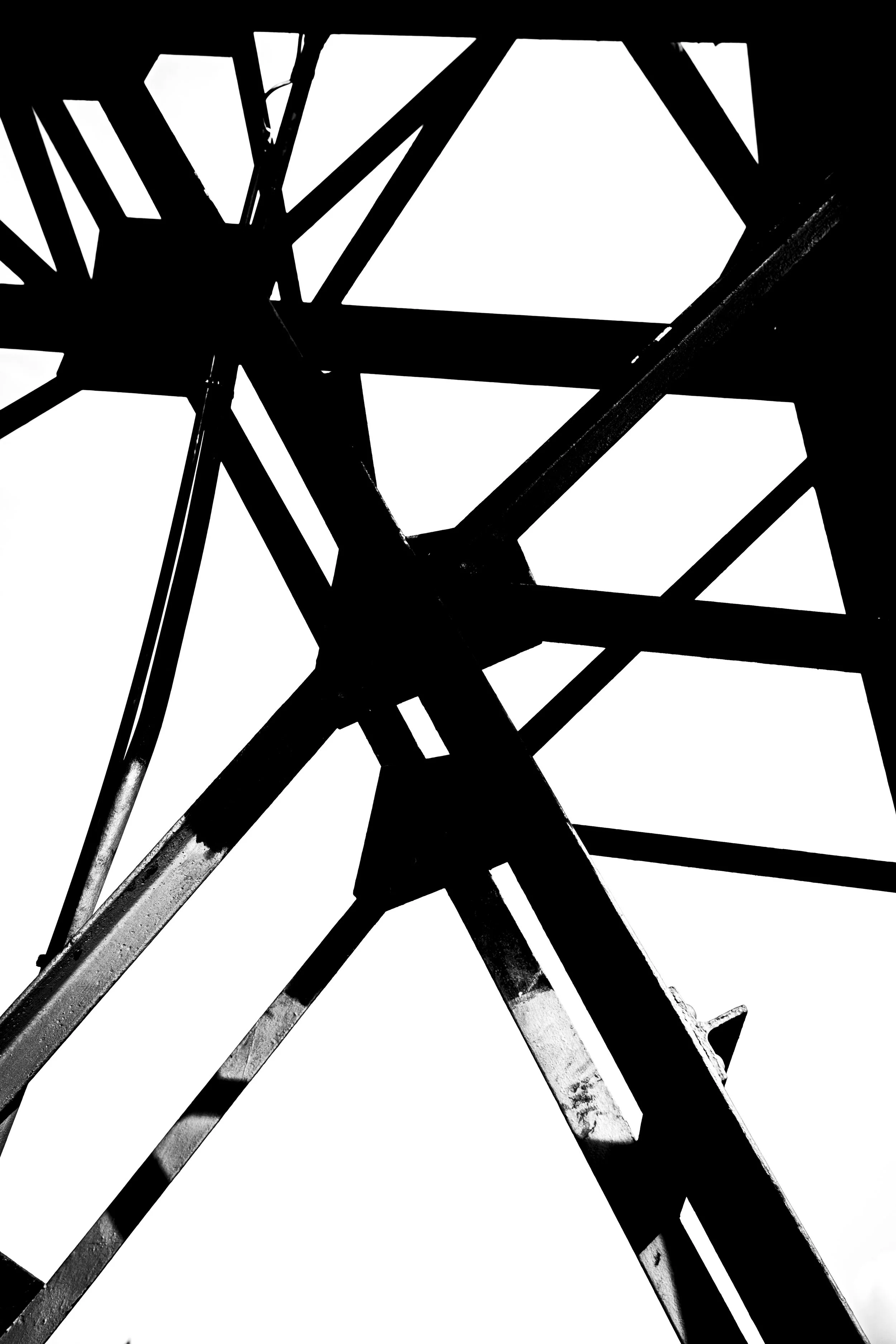 Silhouette of a metallic bridge or framework with geometric lines and angles in black and white.
