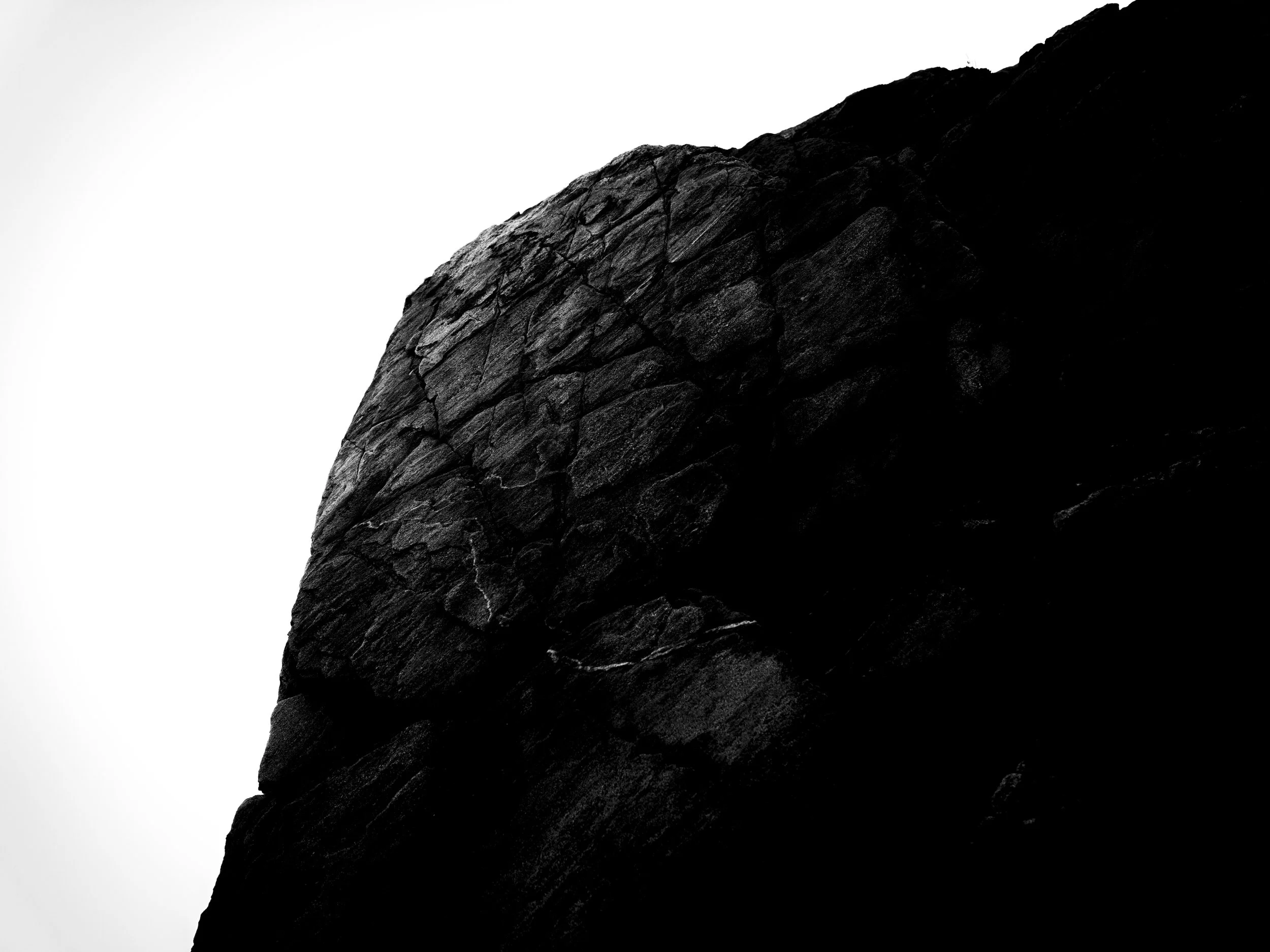 Close-up of a dark, textured rock formation against a plain white background.