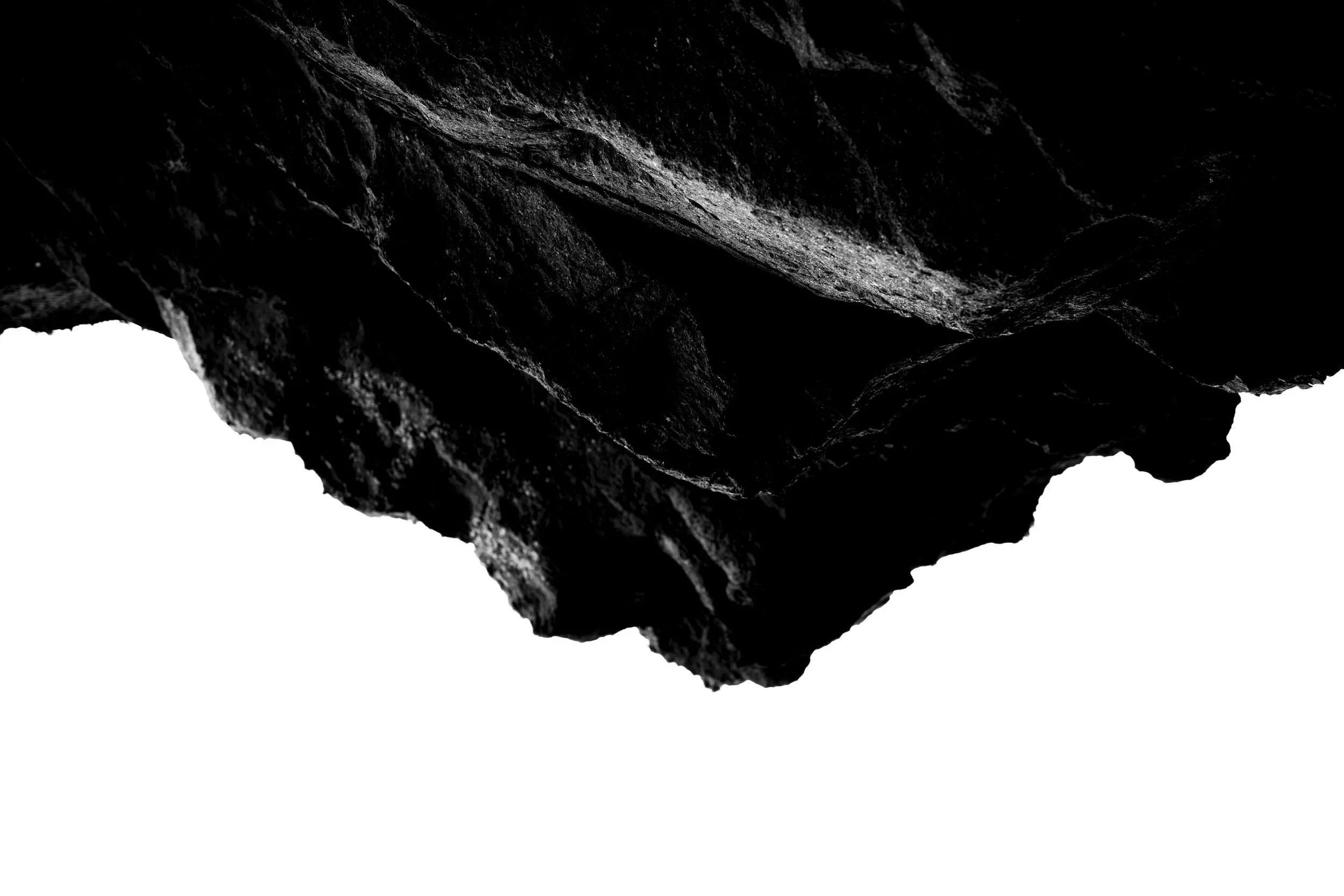 Close-up of dark, textured rocks or stone with a stark white background.