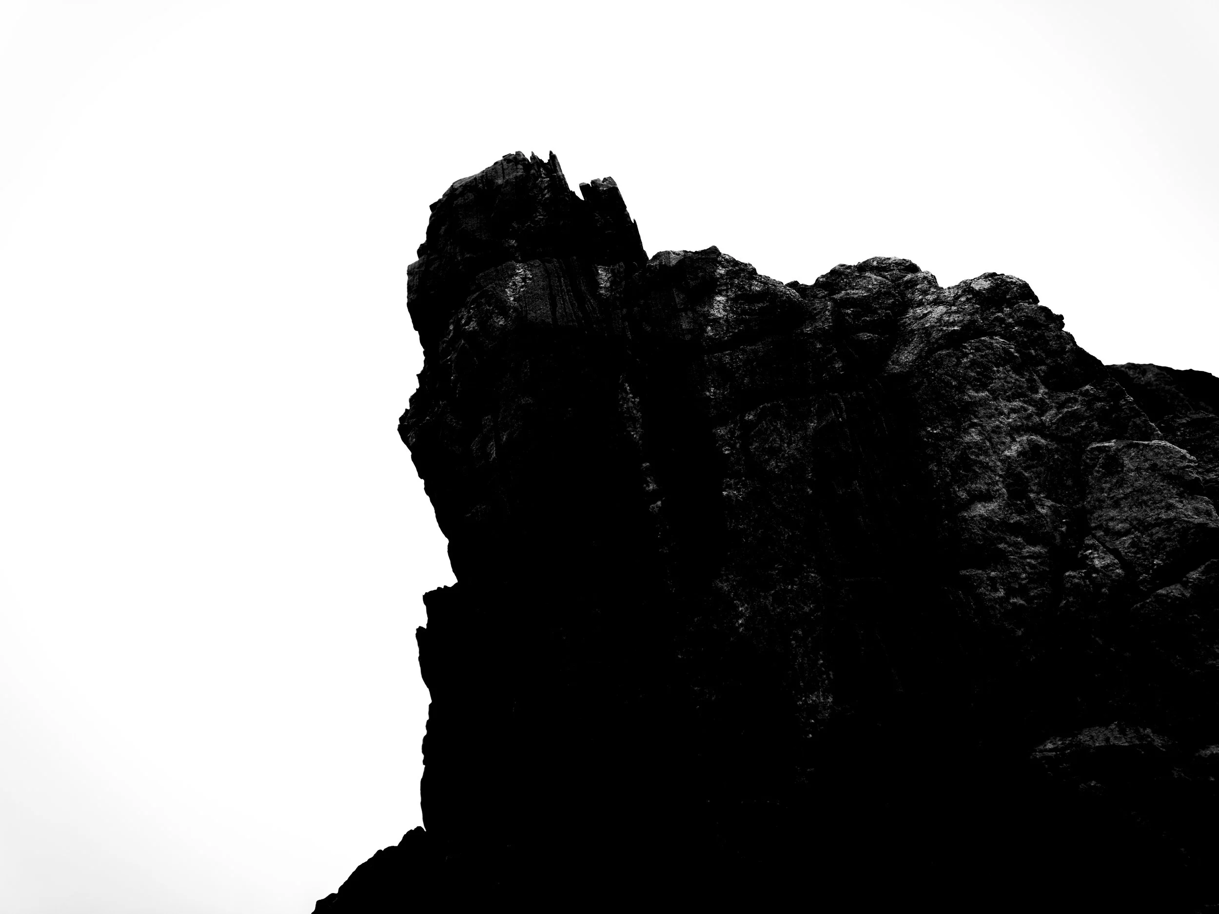 Silhouette of a rugged mountain peak with a clear sky in the background.