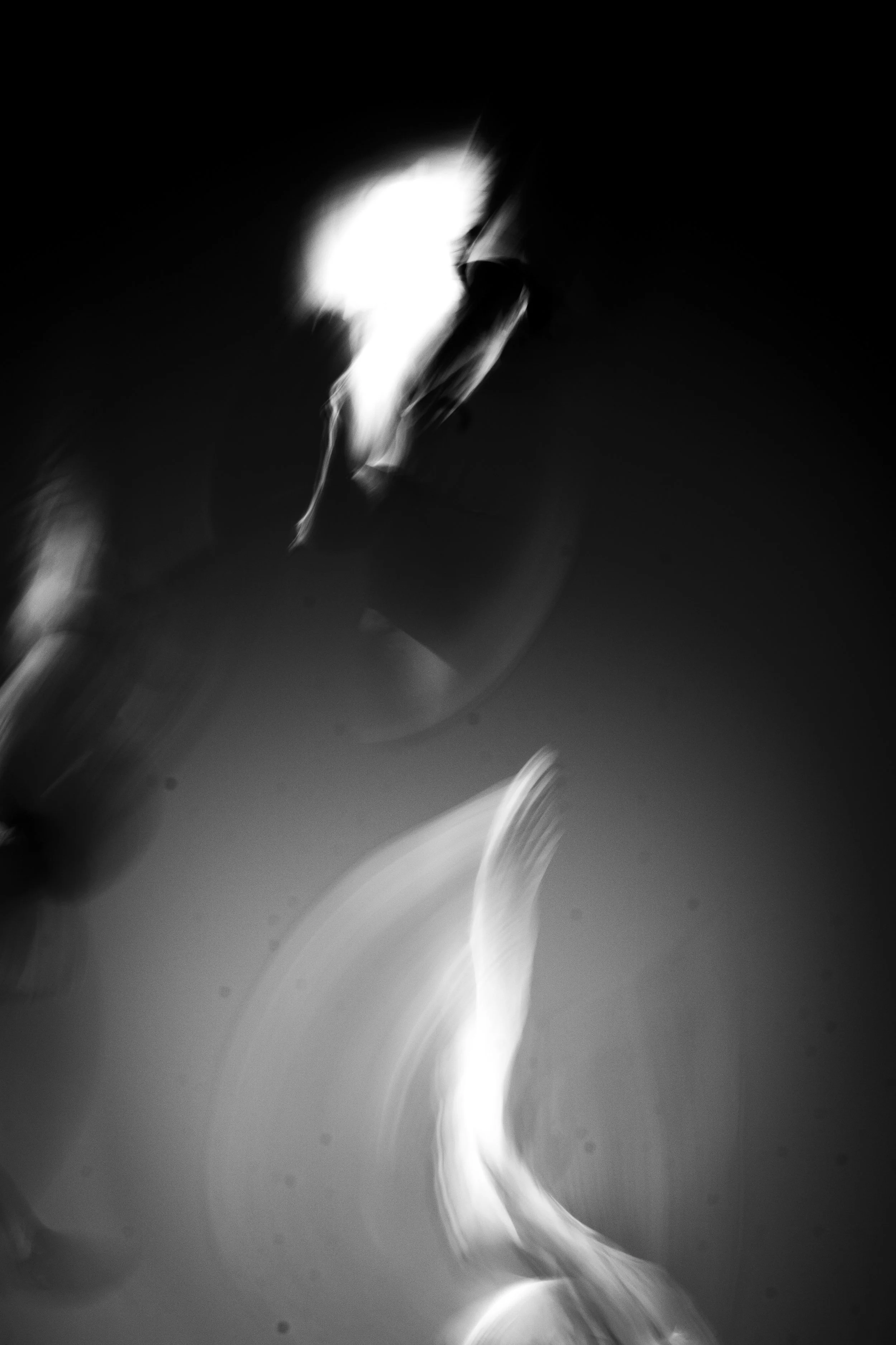 Abstract black and white photo with swirling light streaks, creating a dynamic, blurred motion effect.