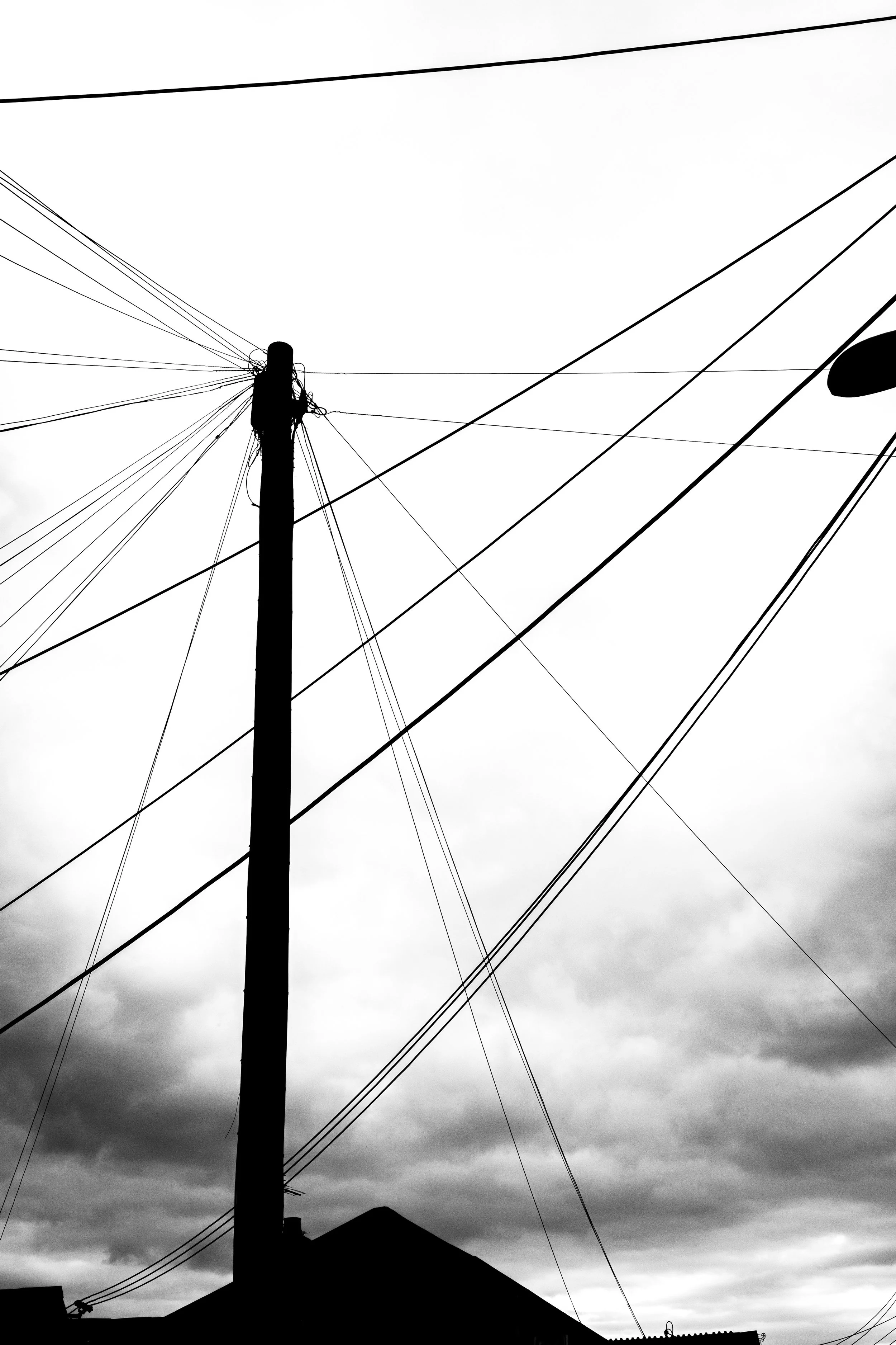 Silhouetted utility pole and power lines against a cloudy, overcast sky.