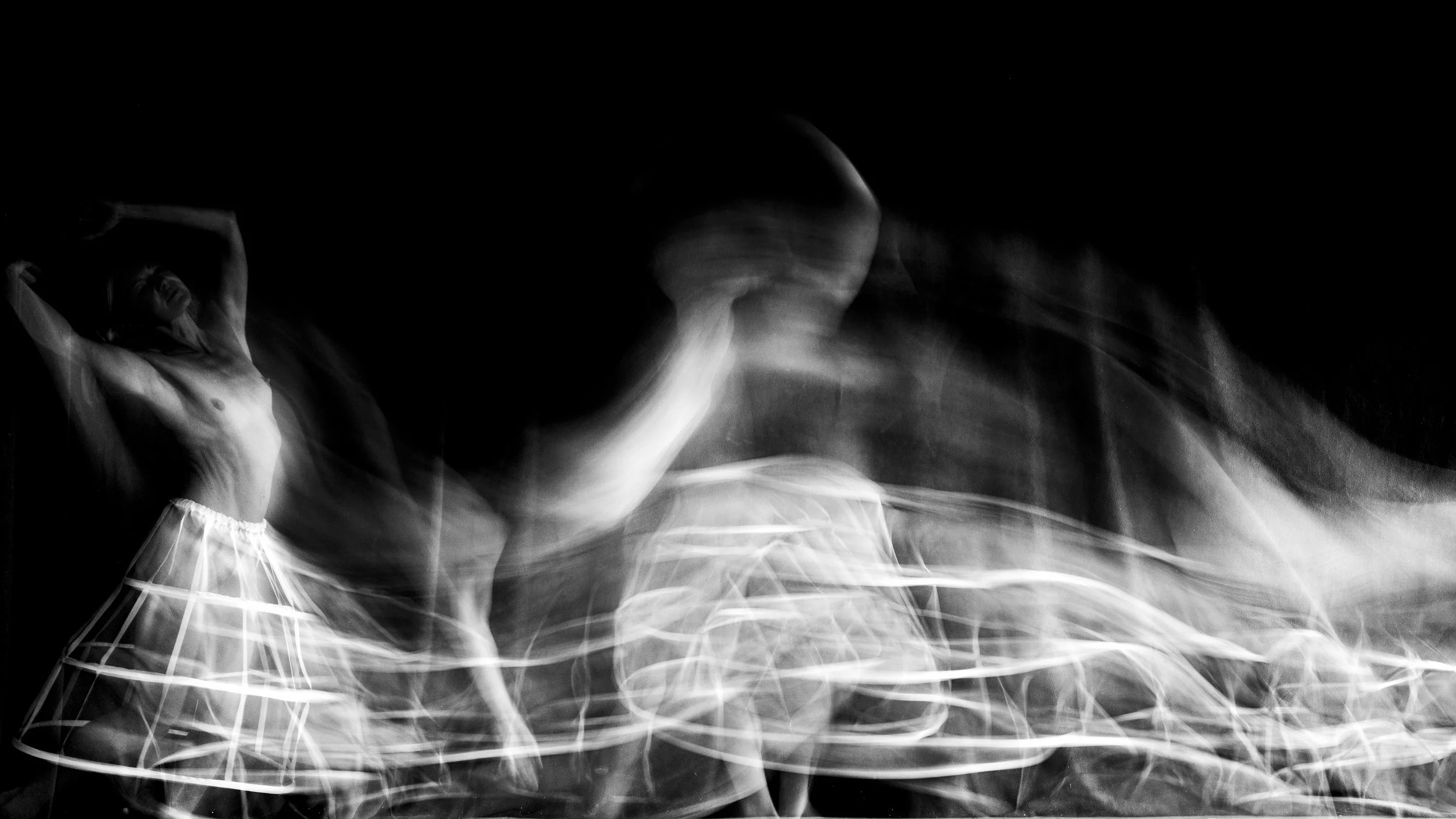 Black and white abstract photo of a person with long hair and a grid-patterned skirt, blurred motion.