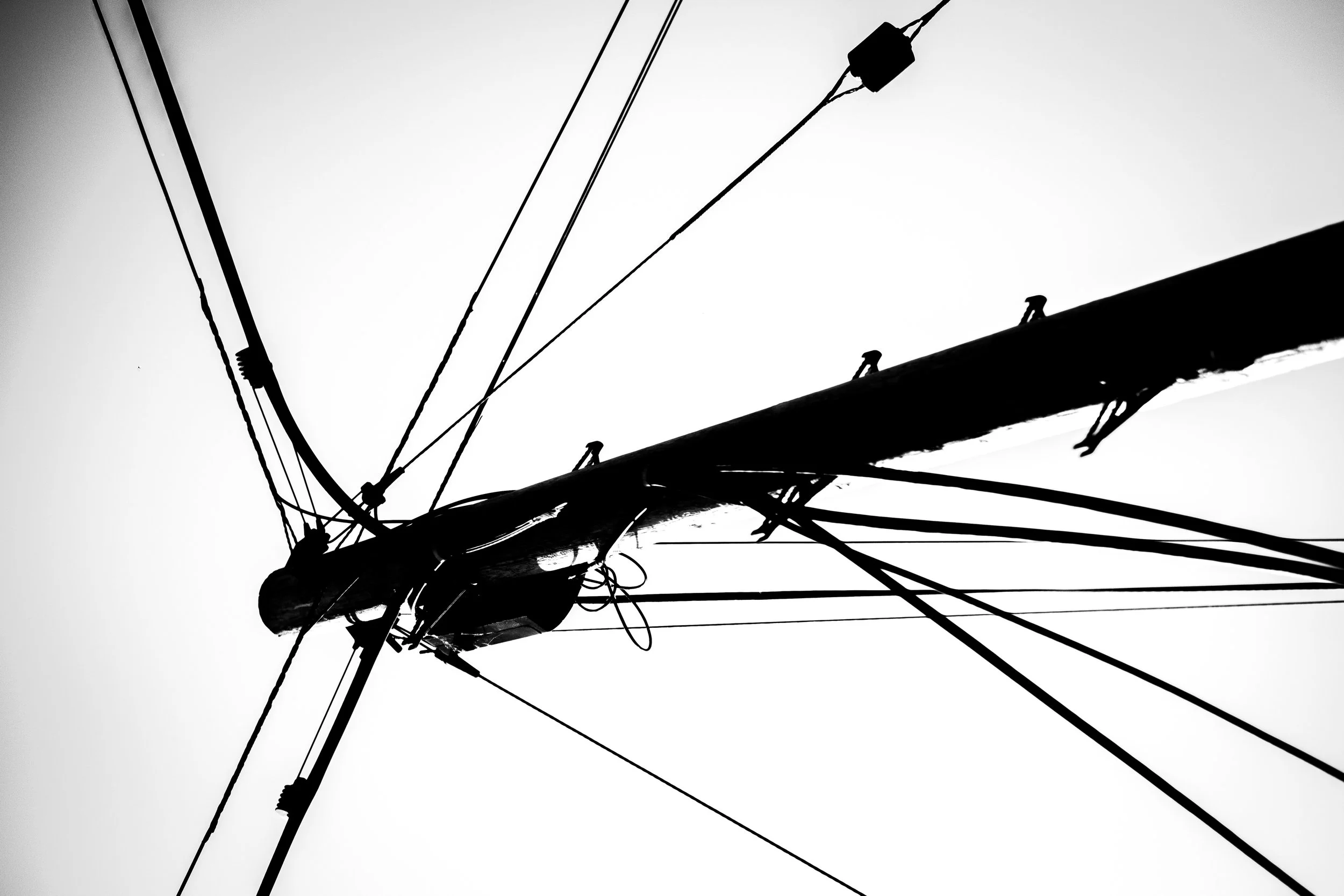 Black and white photograph of electrical power lines and utility pole against a clear sky.