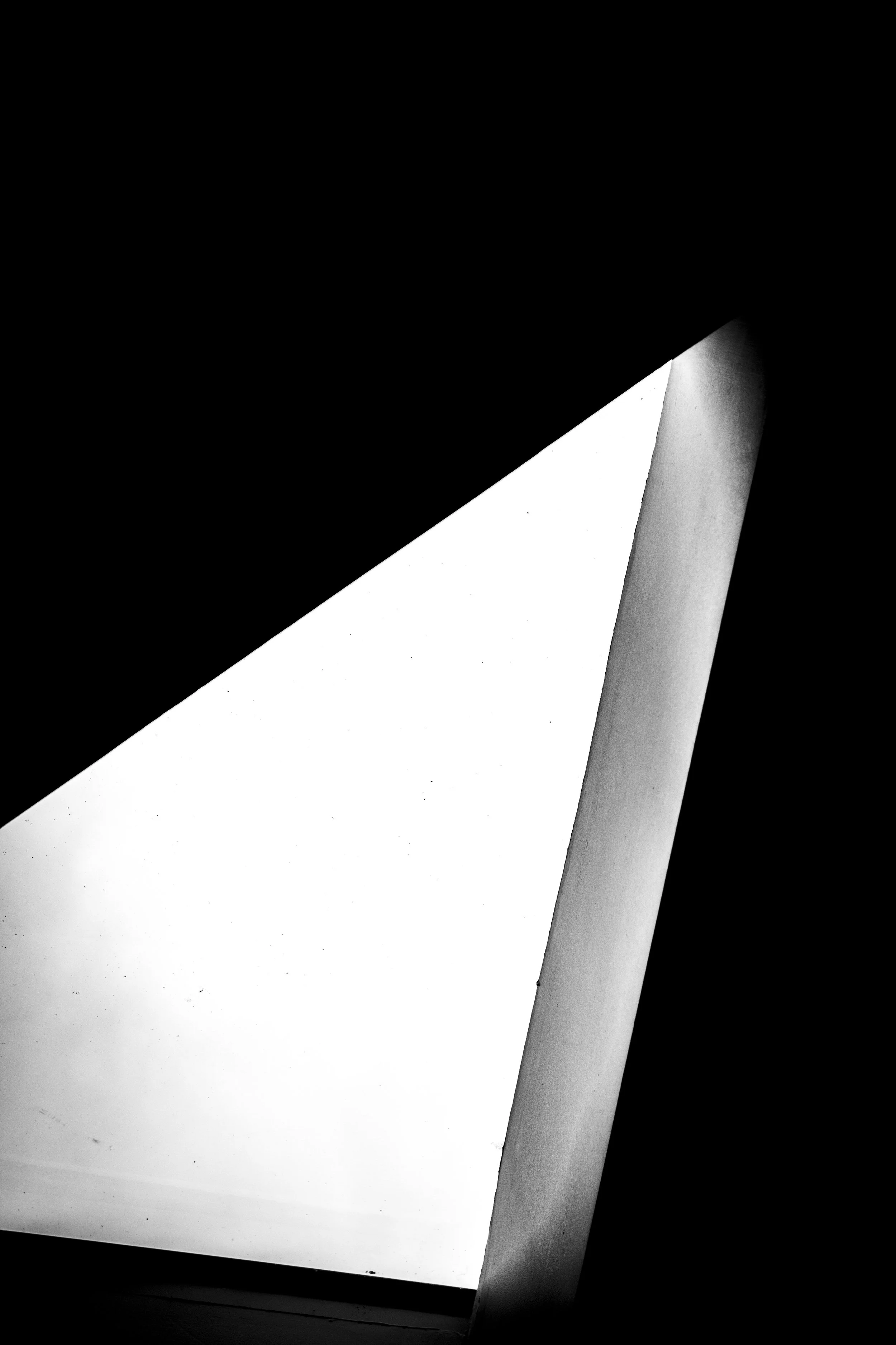 Black and white photograph of an abstract geometric composition featuring light and dark shapes, creating a stark contrast.