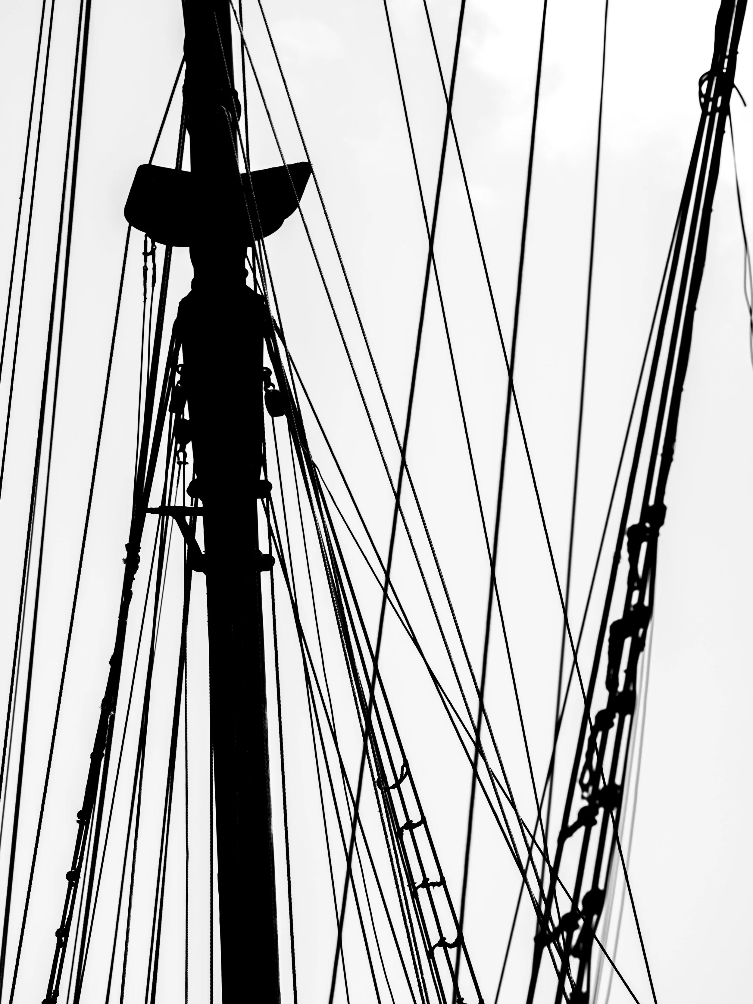 Silhouette of a person climbing power lines against a gray sky.