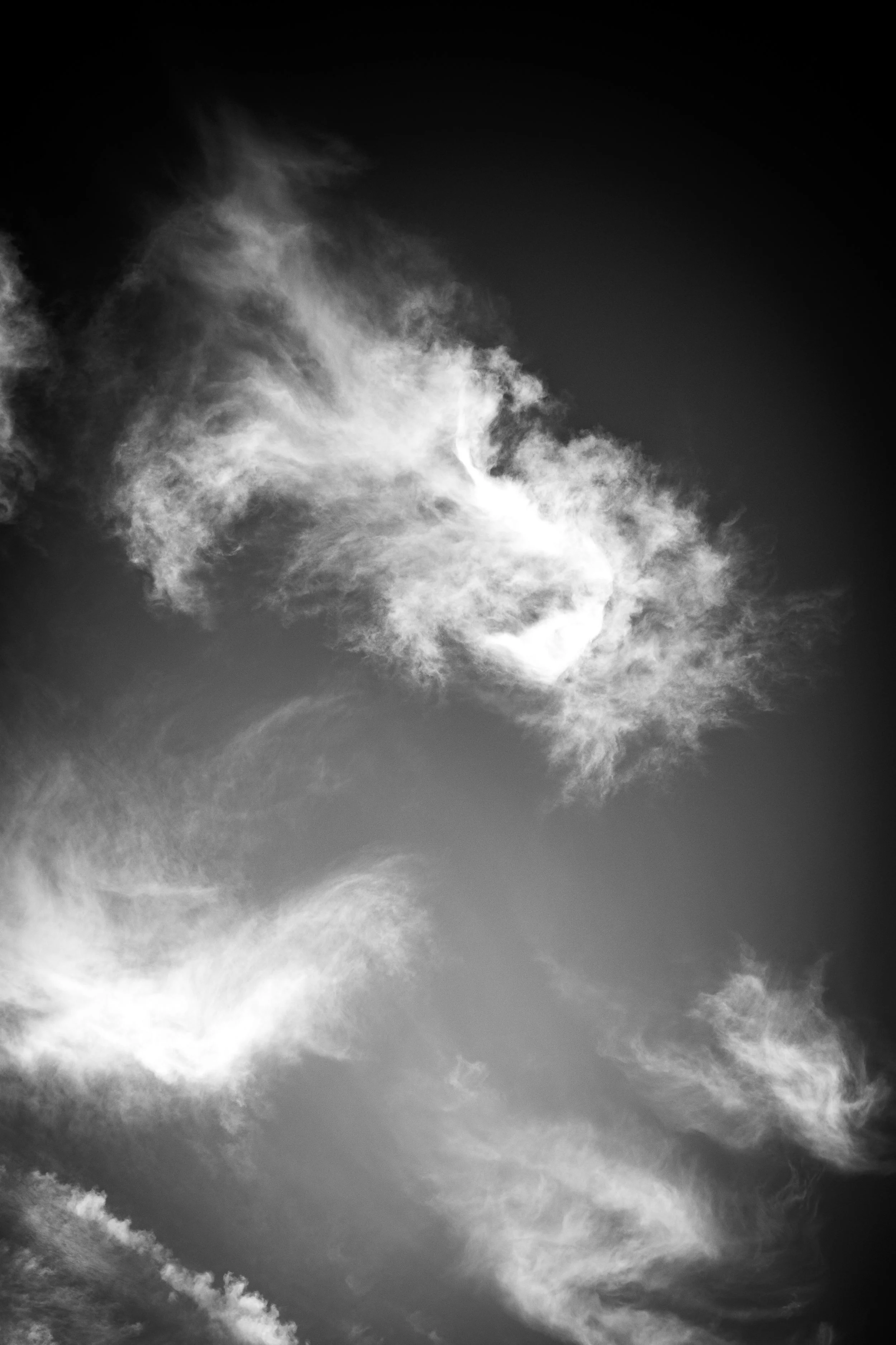 Black and white photo of a cloud-filled sky with clouds forming various shapes and textures.