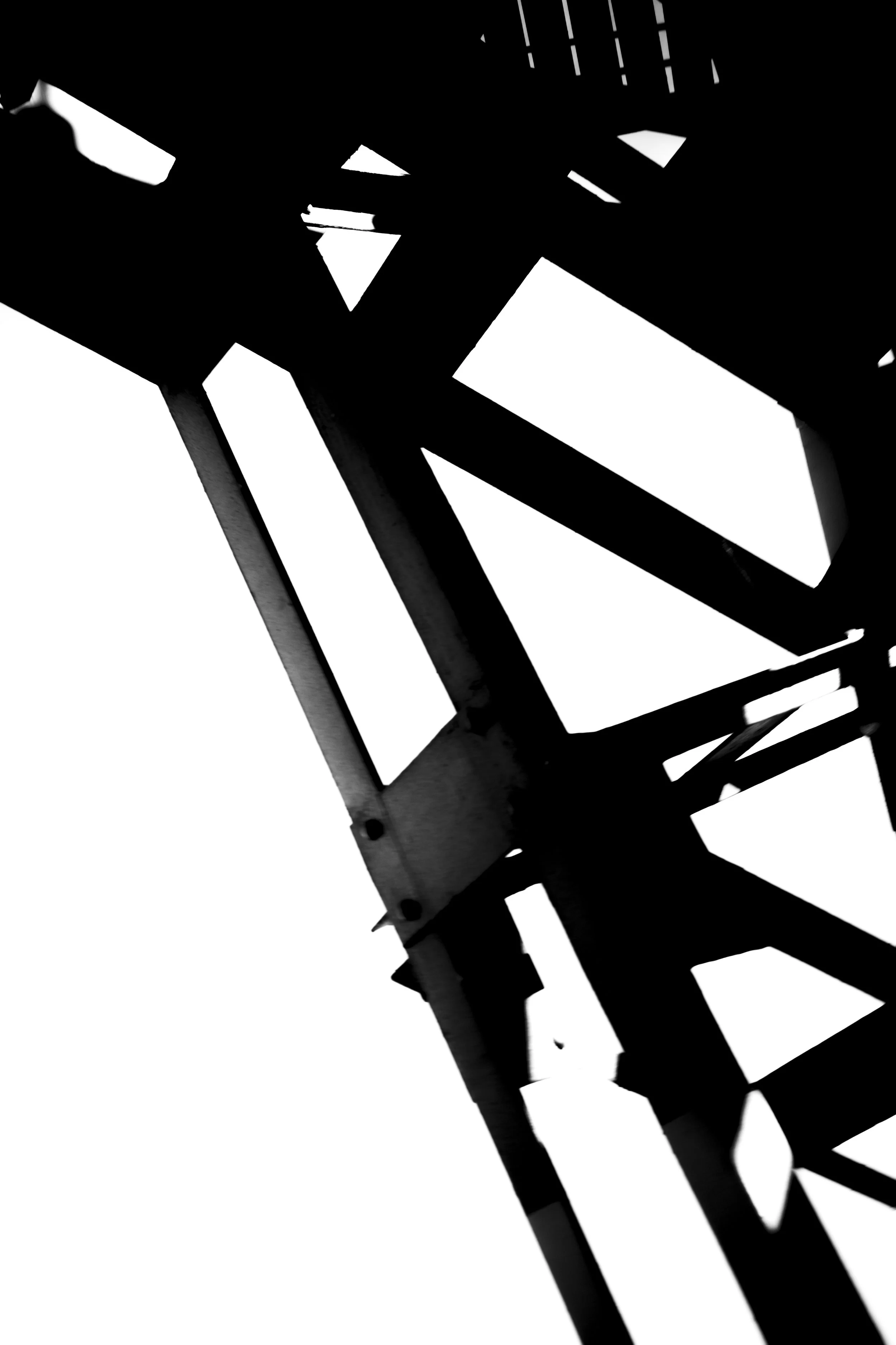 Silhouette of a metallic bridge or framework with geometric lines and angles in black and white.