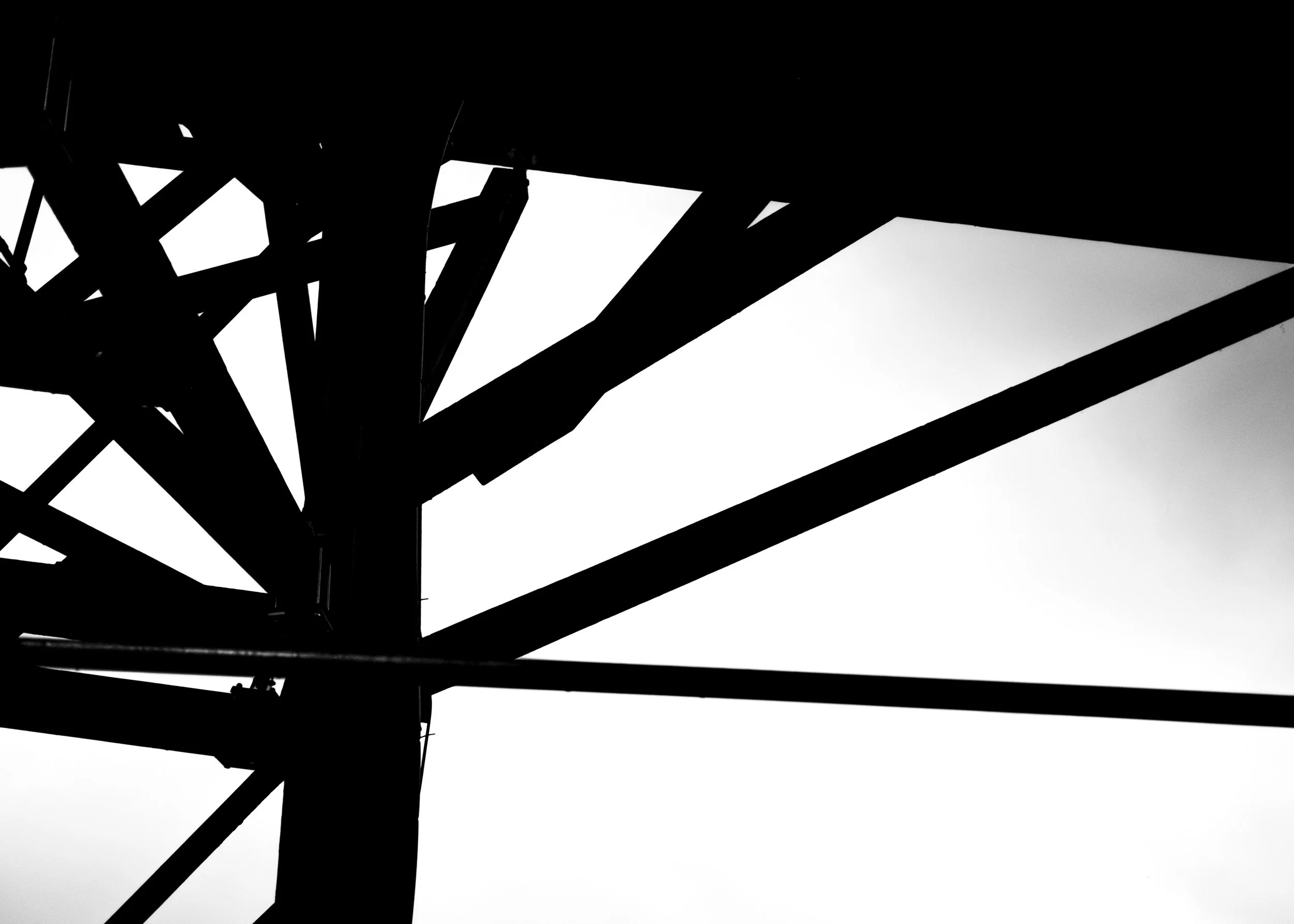 Silhouette of a metallic bridge or framework with geometric lines and angles in black and white.