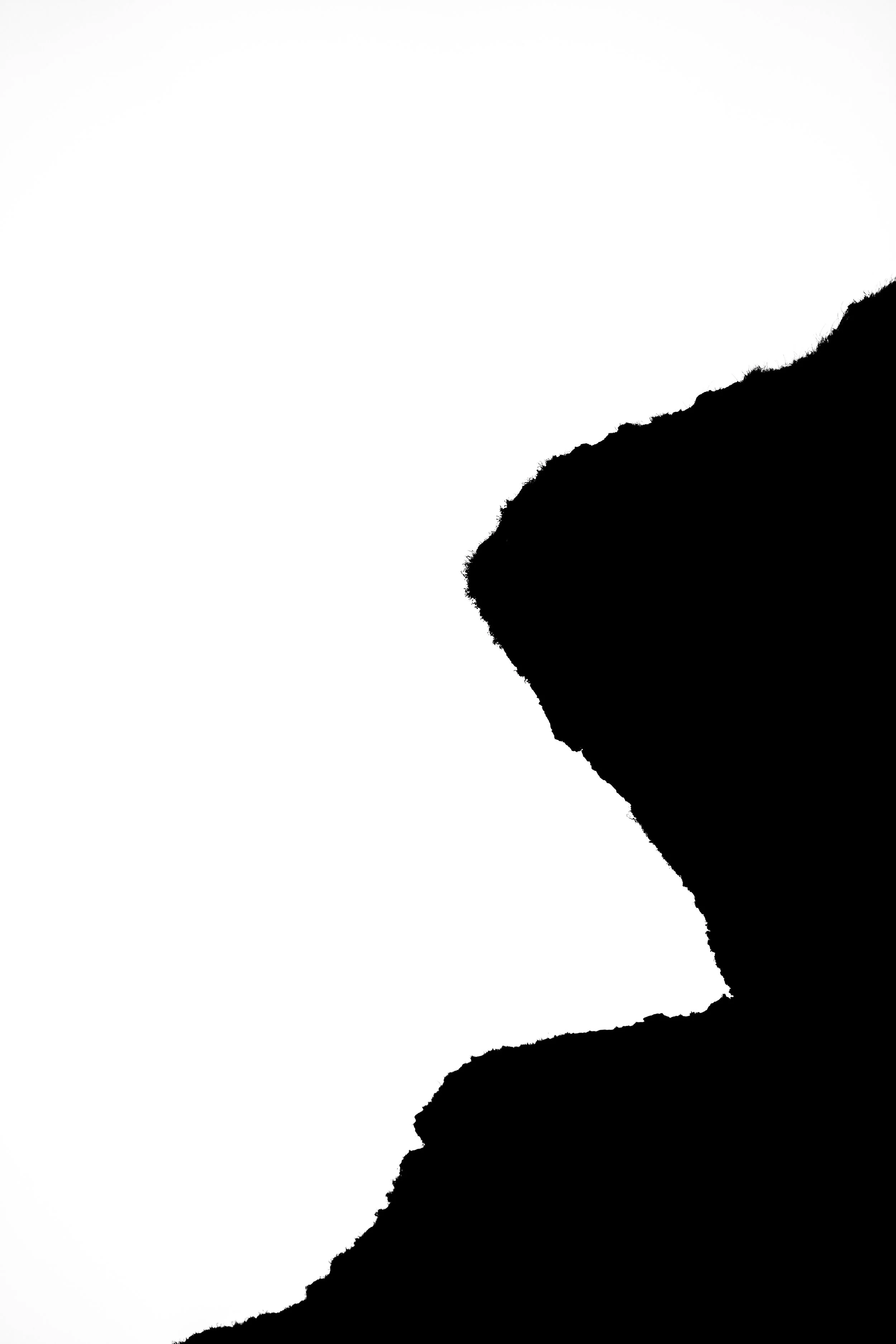Silhouette of a mountain or hill with a rugged edge, black on the right side against a white background.