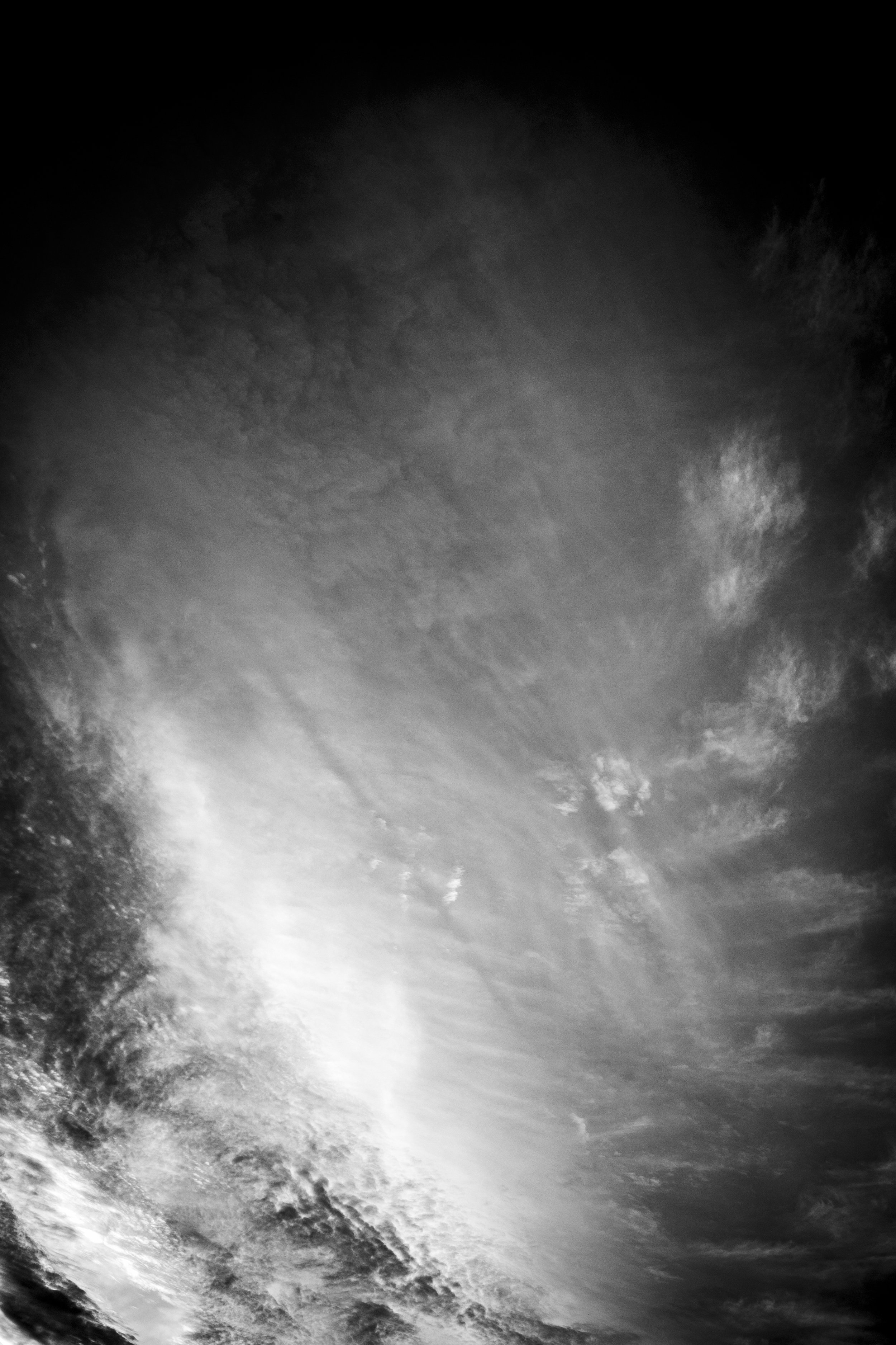 Black and white photograph of a sky with clouds, possibly showing moonlight illuminating the clouds.