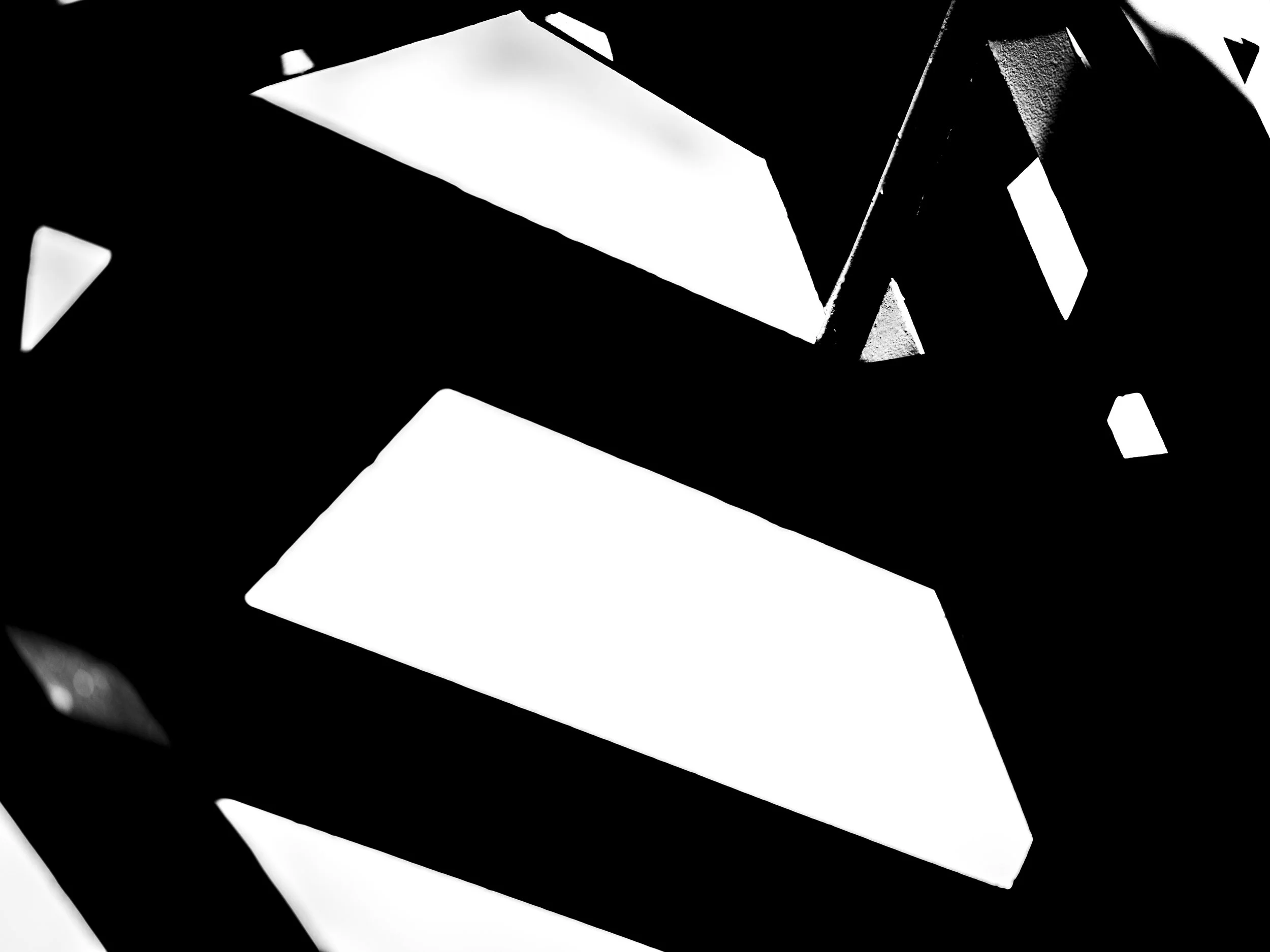 A black and white photo showing light and dark geometric shapes, possibly three-dimensional, with a stark contrast between the black background and white surfaces.