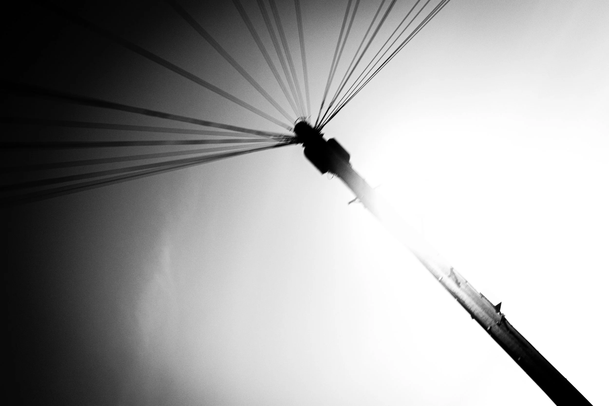 Black and white photograph of a tall pole viewed from below, with the pole extending upwards and out of the frame on the right side.