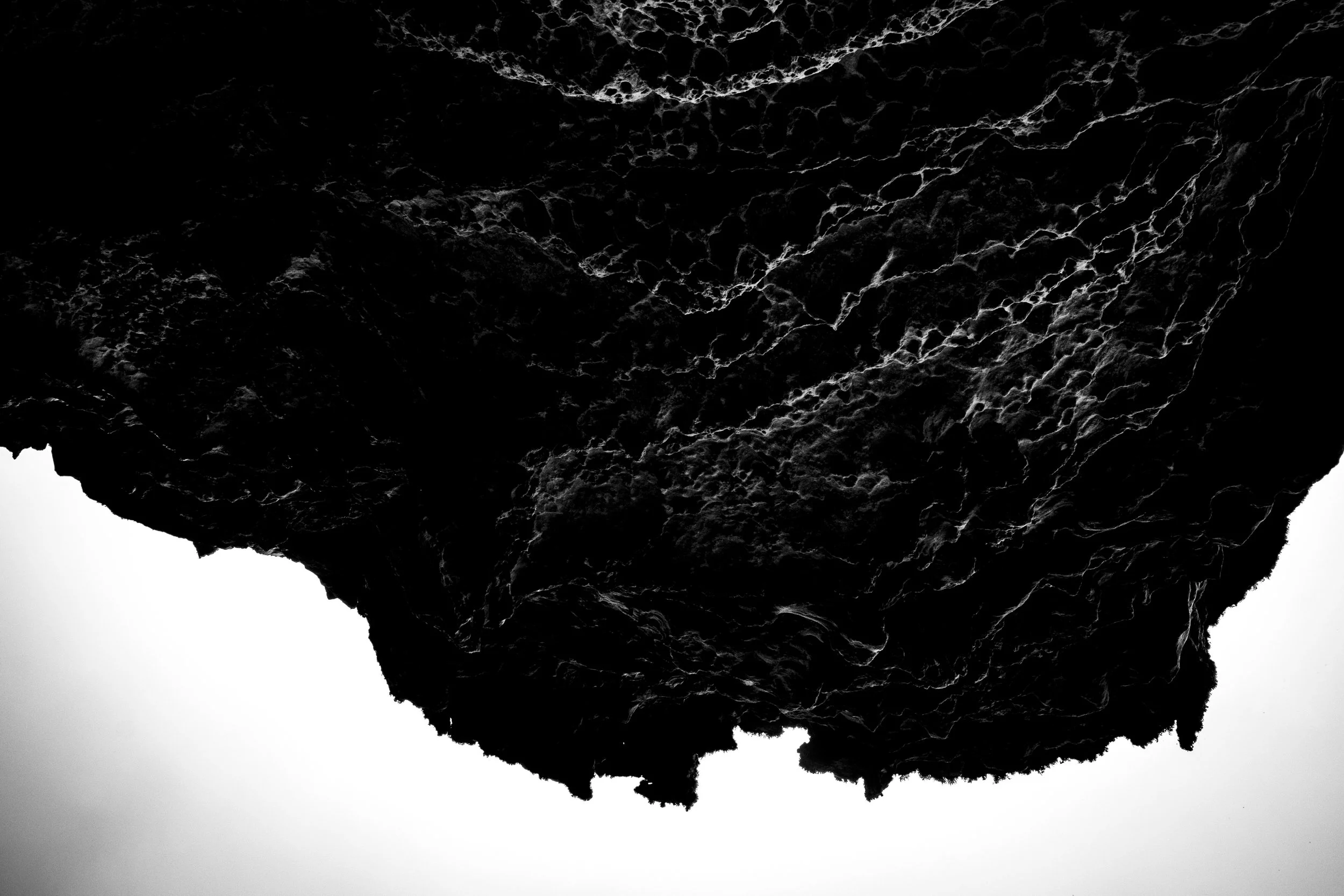 Black silhouette of a mountain with white, icy detail against a gray background.