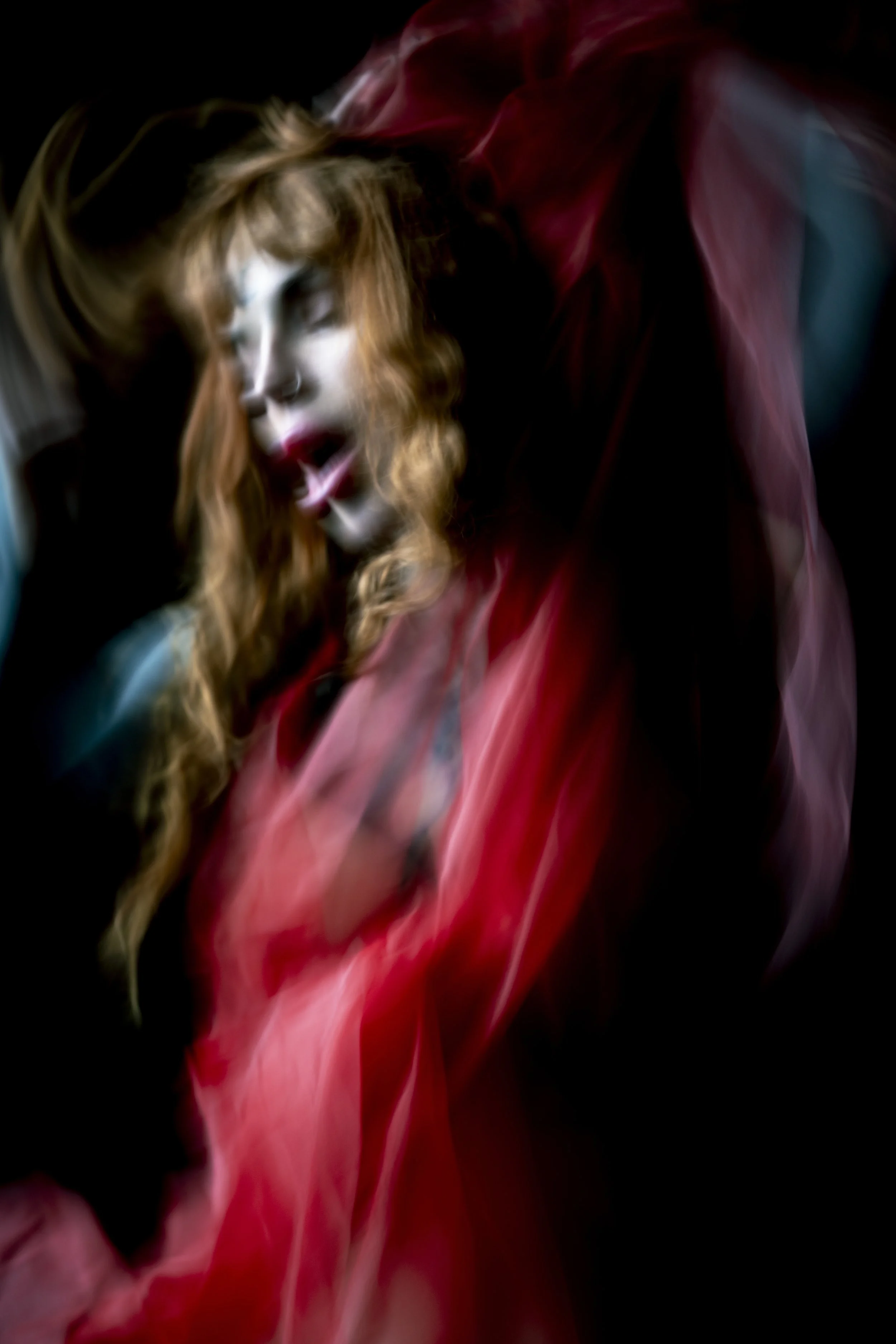 Abstract image featuring swirling red and pinkish smoke or vapor against a black background.