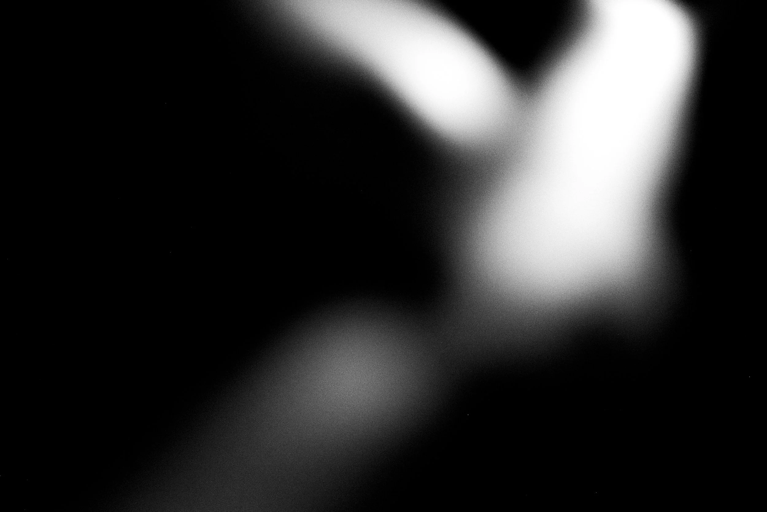 A black and white abstract image with a blurred face, showing only some facial features and no clear details.