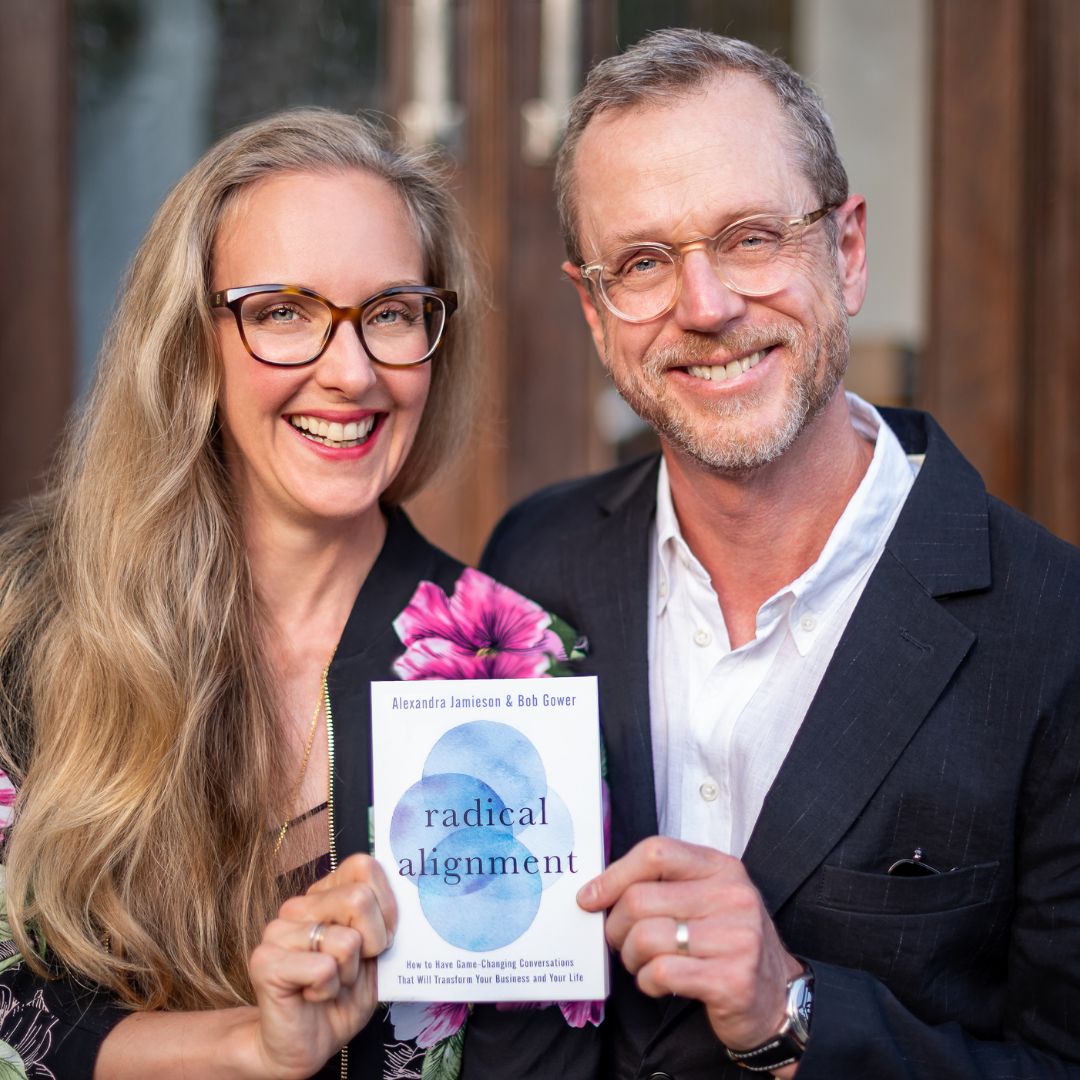 Two people smiling and holding a book titled 'Radical Alignment' by Alexandra Jamieson and Bob Gower.