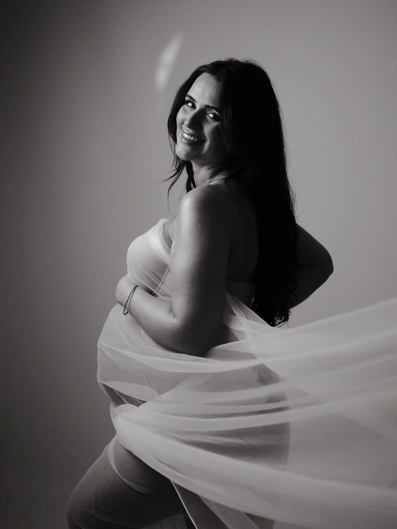 Künstlerisches Schwarz-Weiß-Portrait einer Schwangeren. Ästhetische Babybauch-Fotografie im Fotostudio in Frankfurt.