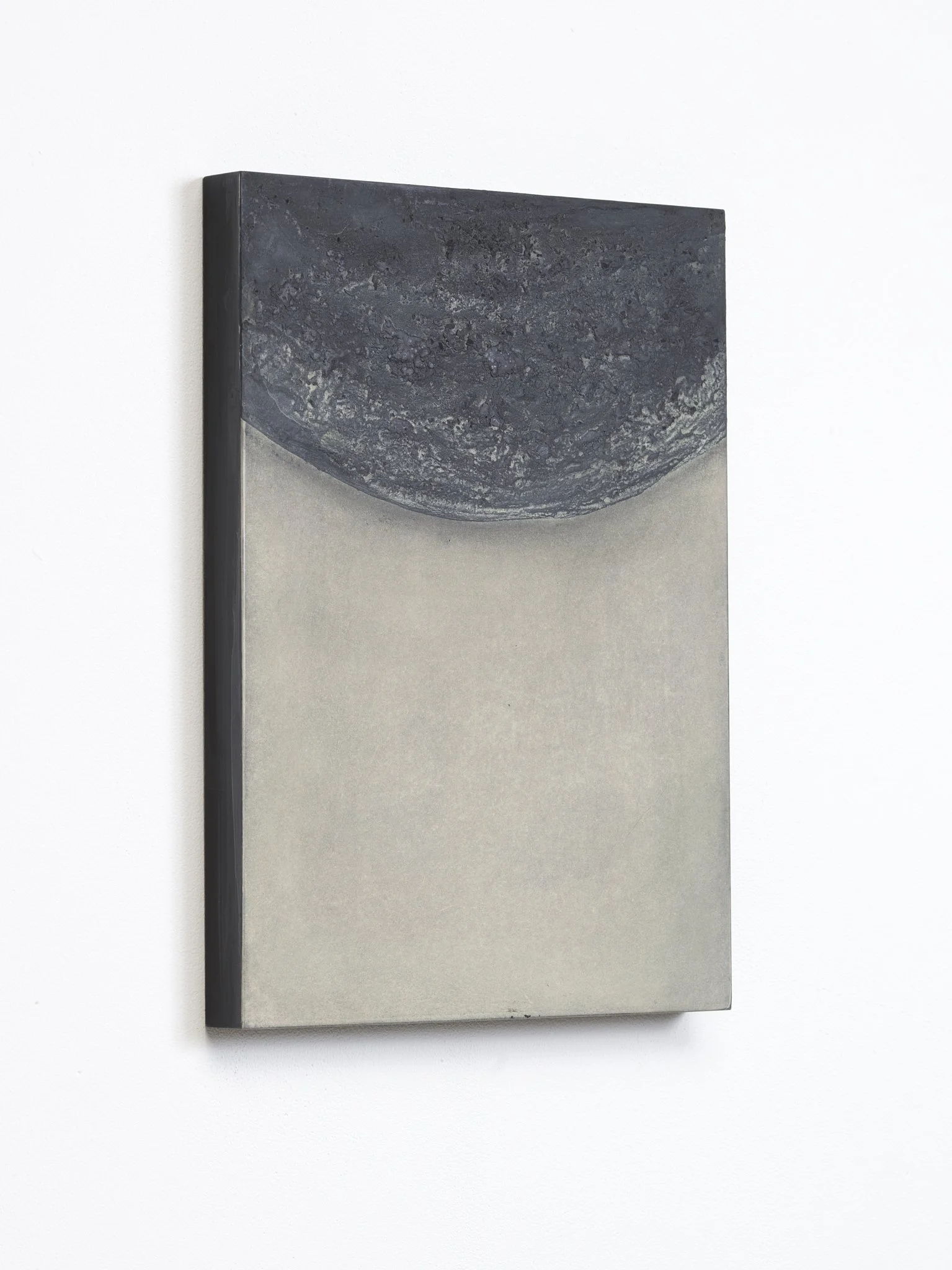 A minimalist wall mirror with a black marble top and a silver frame, mounted on a white wall.