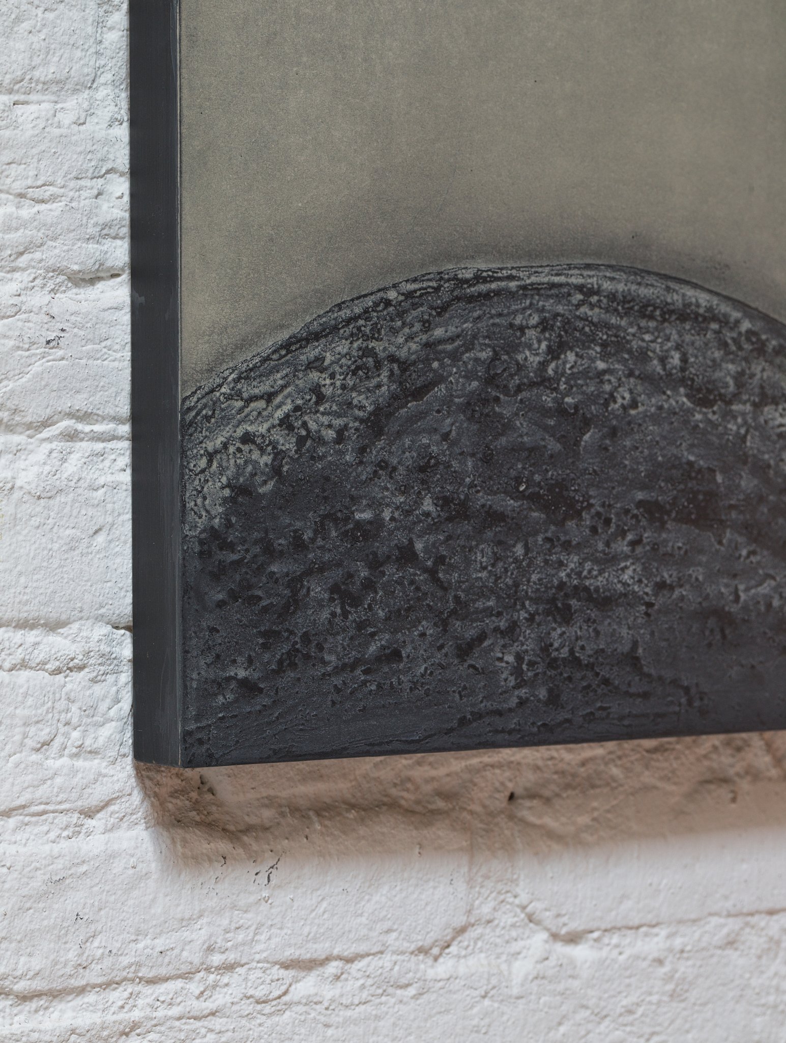 Close-up of a rectangular black object mounted on a white brick wall.