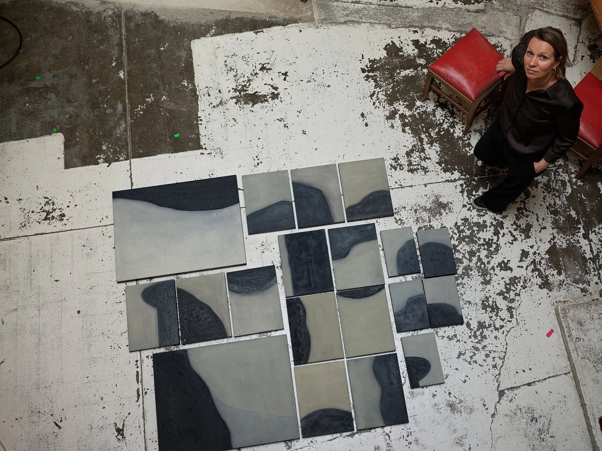 Ekaterina Galera arranging a series of abstract artworks on the studio floor.