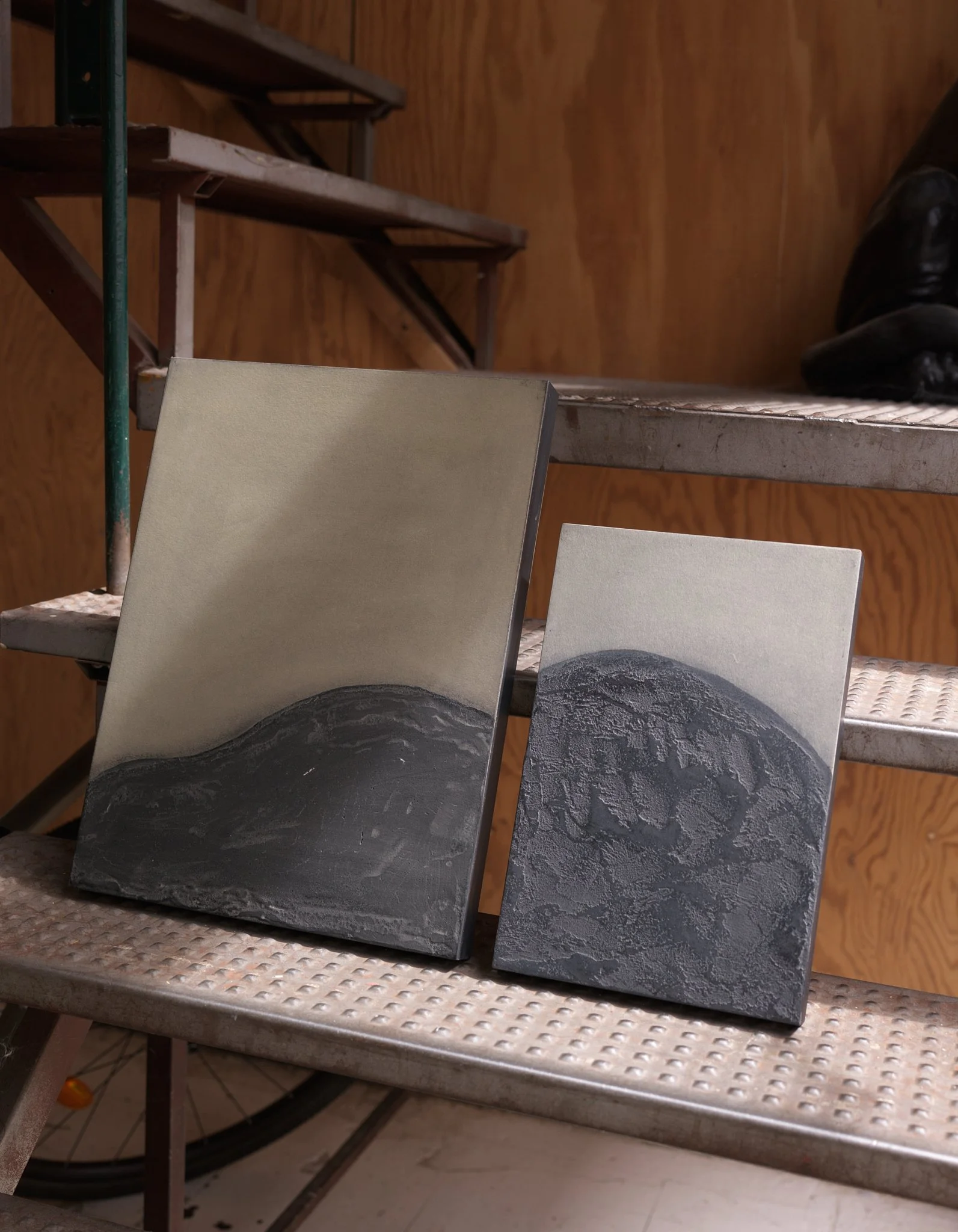 Two abstract mixed-media artworks by Ekaterina Galera displayed on a metal studio staircase.