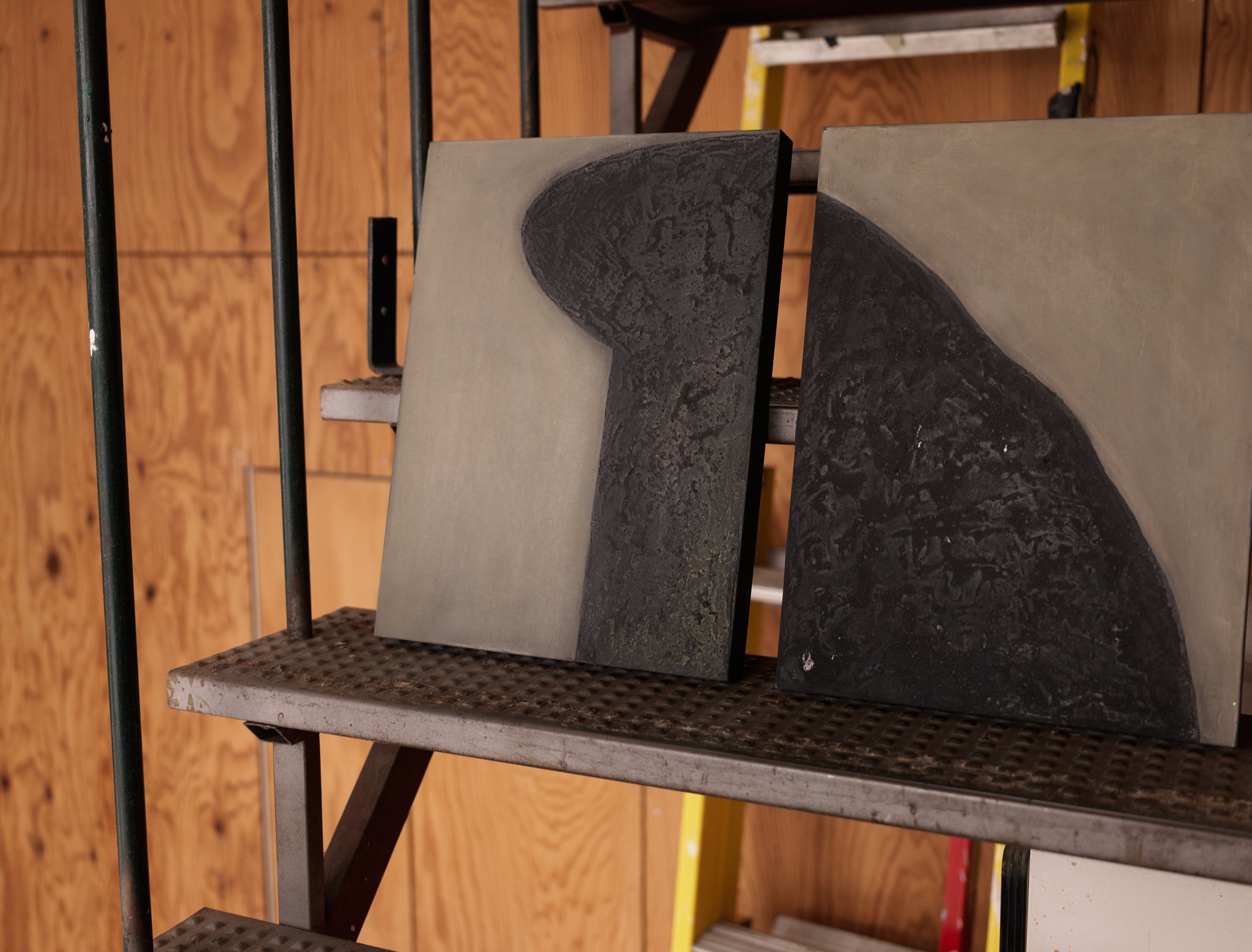 A close-up of black granite or marble slabs on a metal shelf with black bars in a warehouse or storage area.