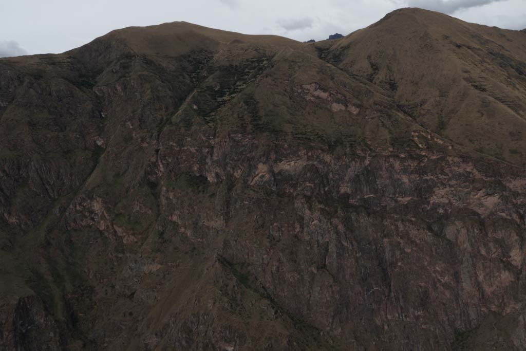 Photo of a mountainous landscape with a rugged, steep slope and overcast sky.