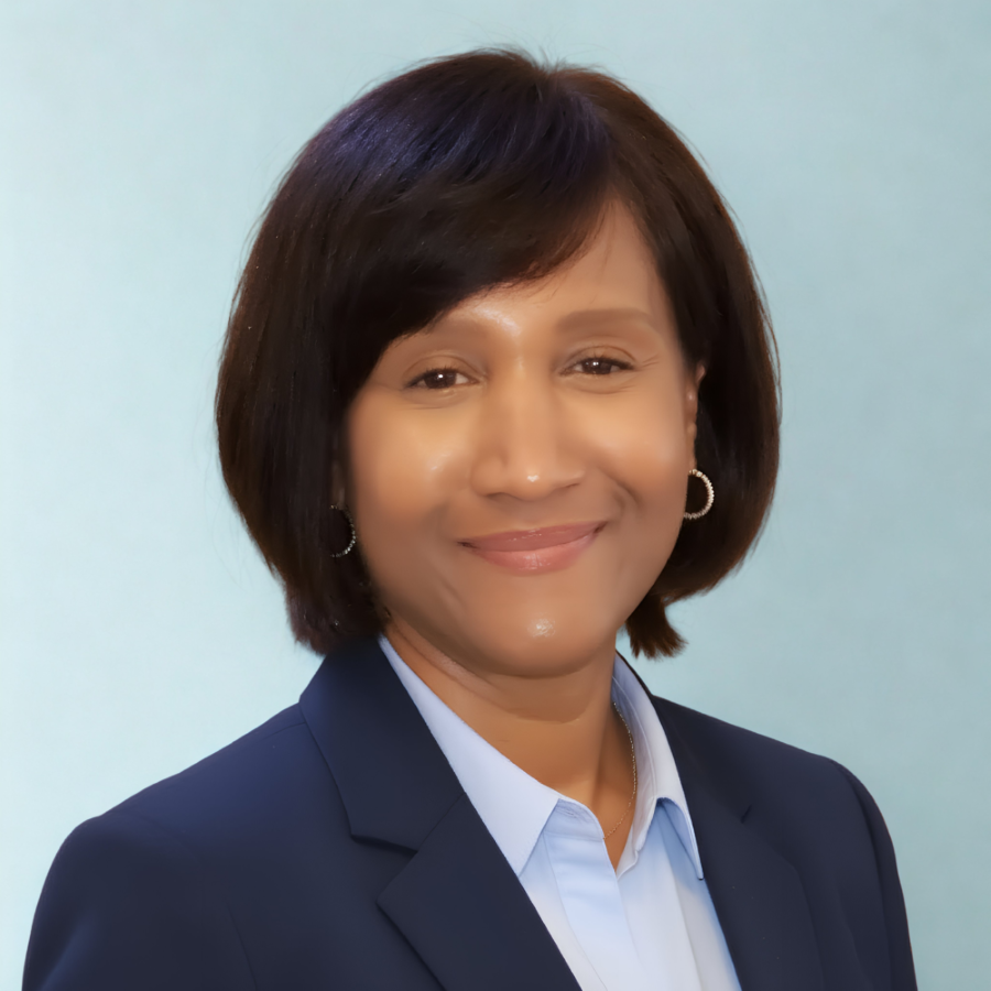 Professional woman with shoulder-length dark hair wearing a navy blazer and light blue blouse, smiling against a light blue background.