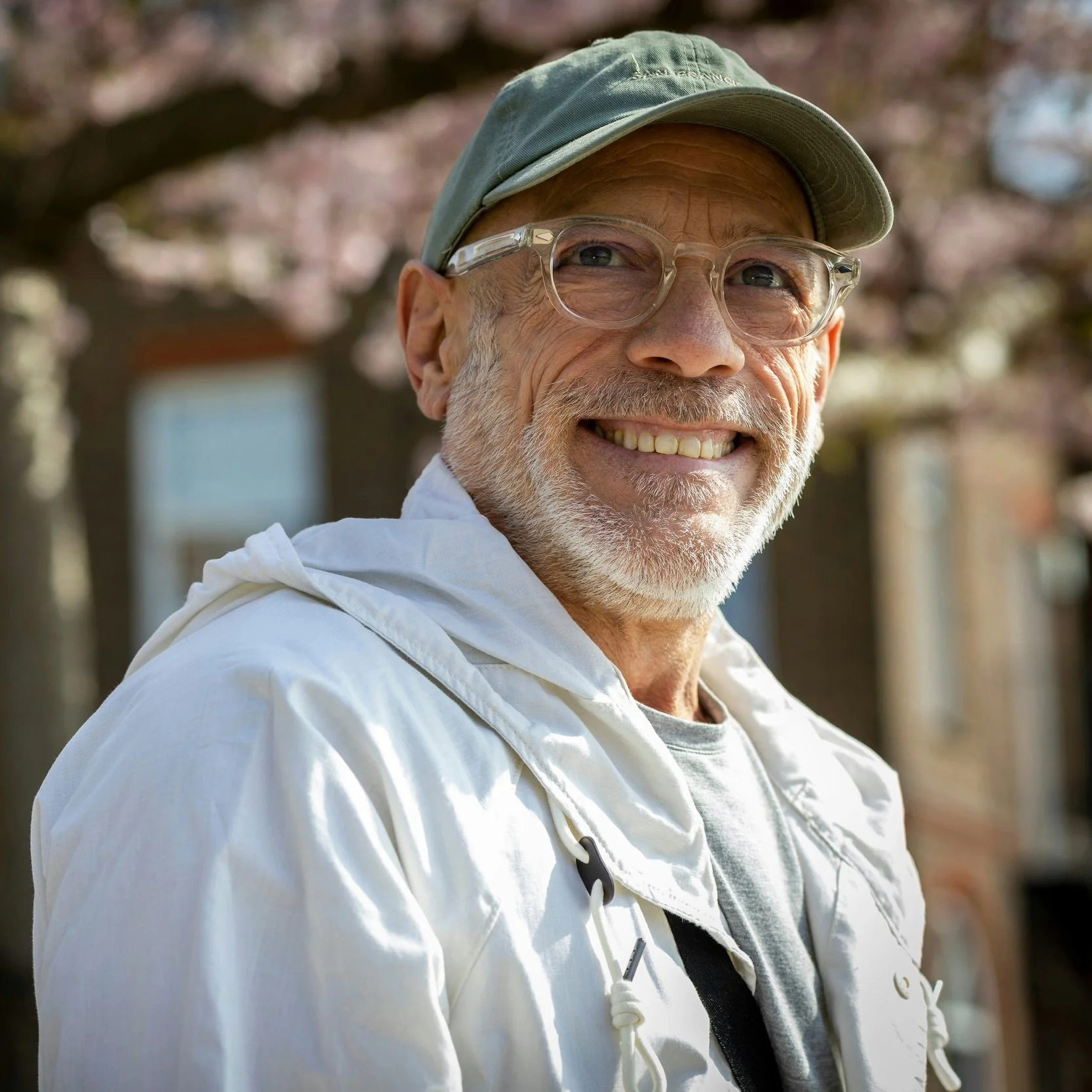 smiling middle aged man with round clear glasses, green tshirt and short white beard