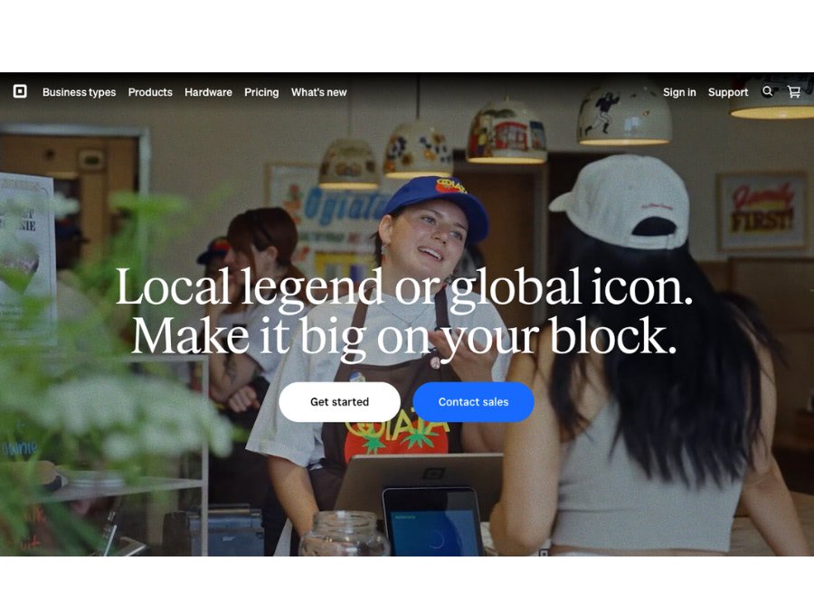 Screenshot of a business website homepage displaying two people working behind a counter in a casual setting, with a welcoming message about local and global branding. There are menu options at the top and call-to-action buttons.