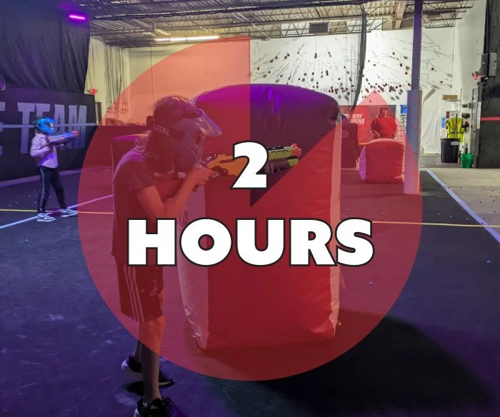 Kids playing laser tag in an indoor gaming arena with laser guns and inflatable cover, overlaid with a red circle and white text reading "2 HOURS".