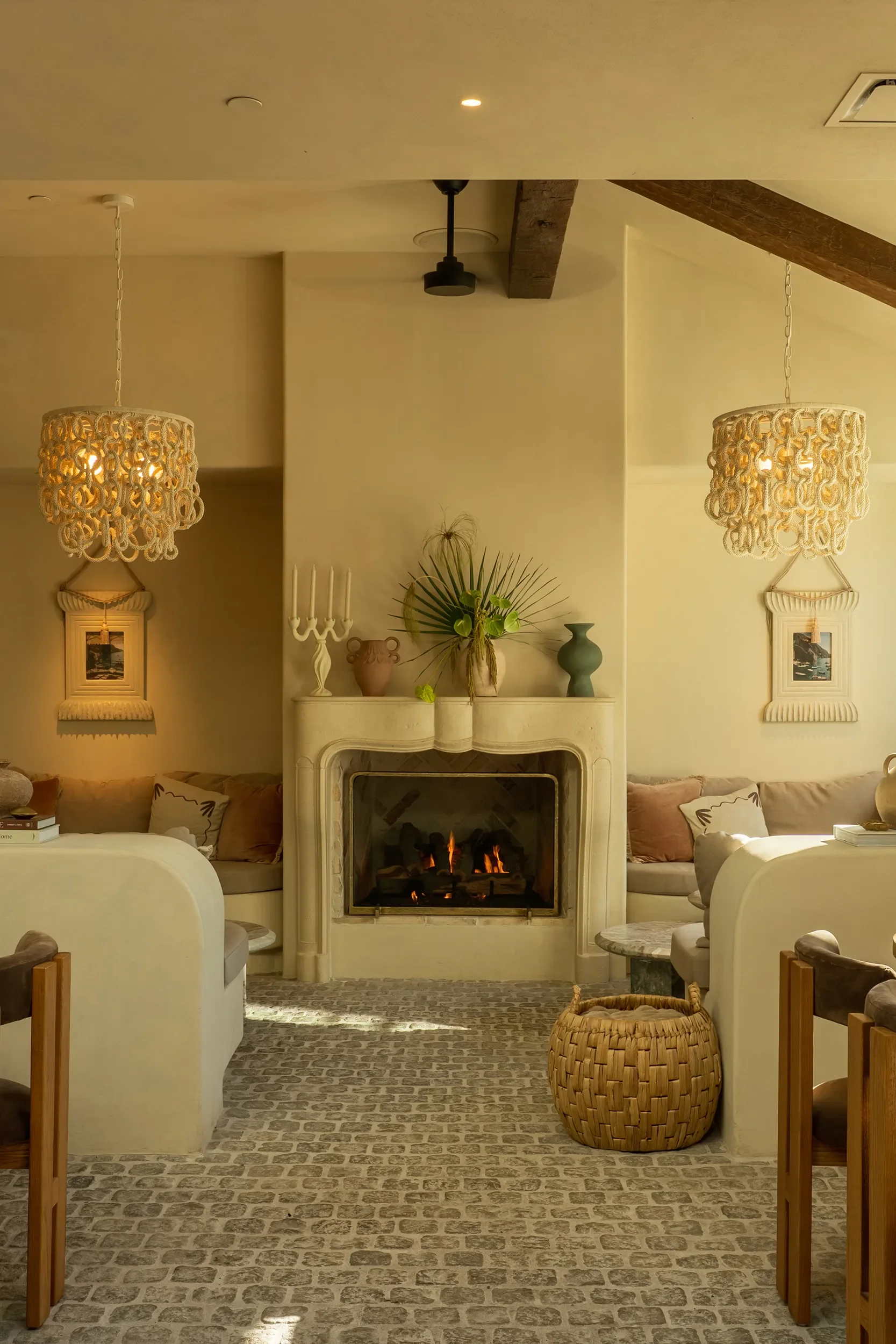 Plaster fireplace and woven chandeliers in a private dining room at By The Sea with curved banquette seating