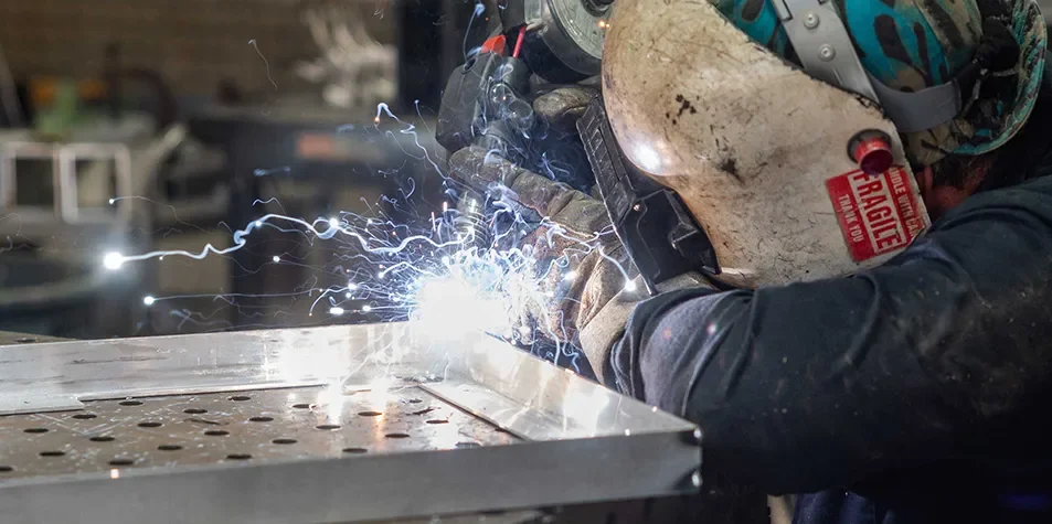 Tecture AF metalworker welder joining steel on a table in the Tecture fabrication shop.