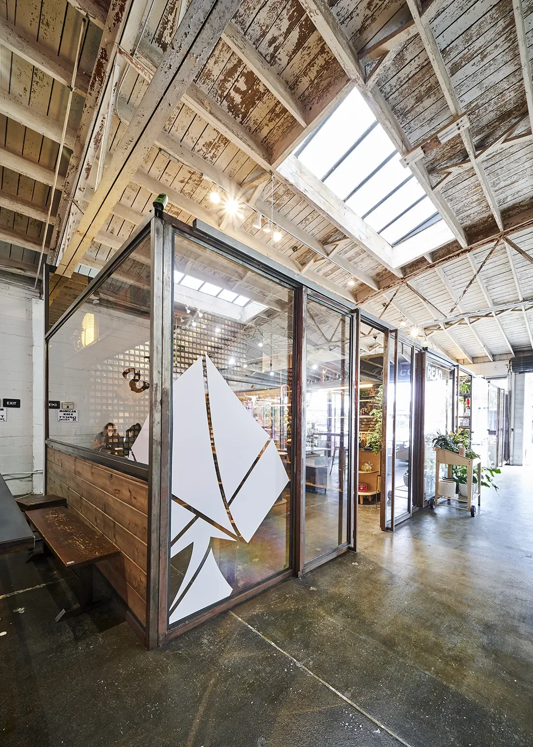 Art of Play's glass storefront with metal framing, wood panels, and an oversized white space graphic.