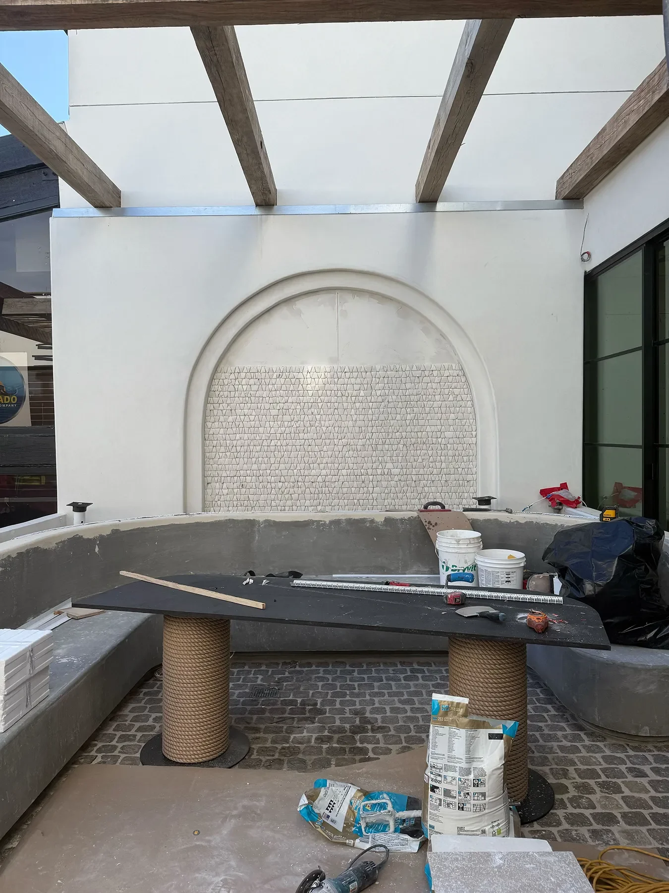 The arched mosaic tile panel going in above the patio booth seating at By The Sea, Coronado