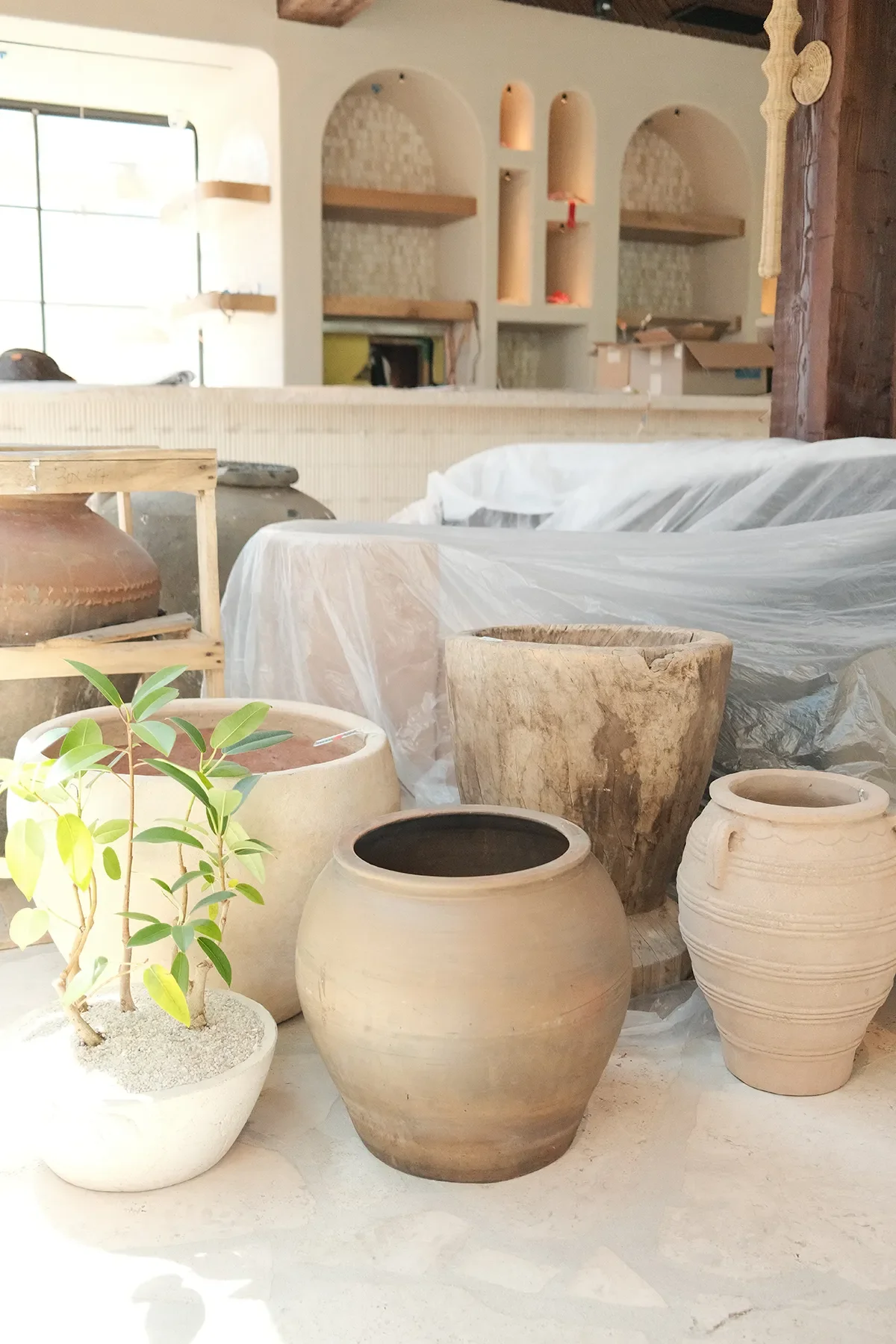 Terracotta vessels waiting to be placed in front of the tiled arched niches at By The Sea