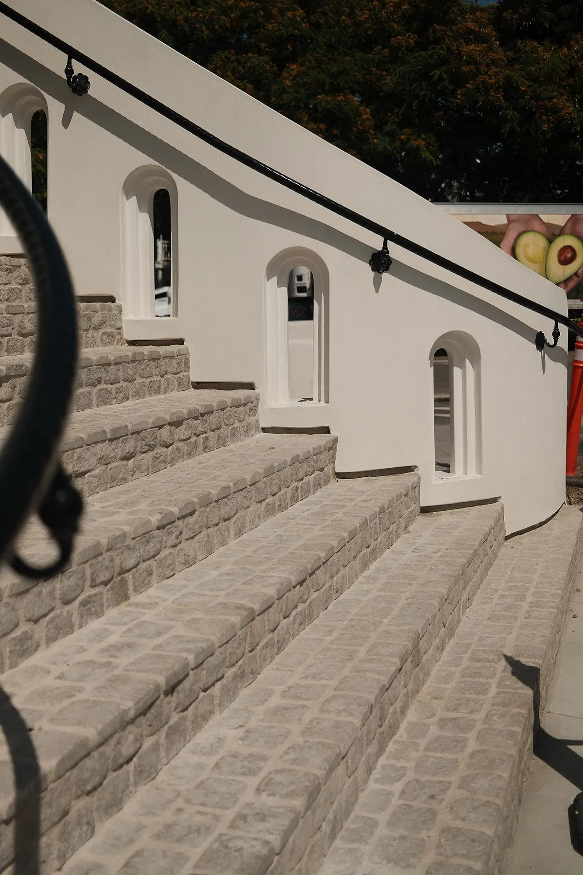 The cobblestone entry stair and dark handrail against white plaster at By The Sea, Coronado