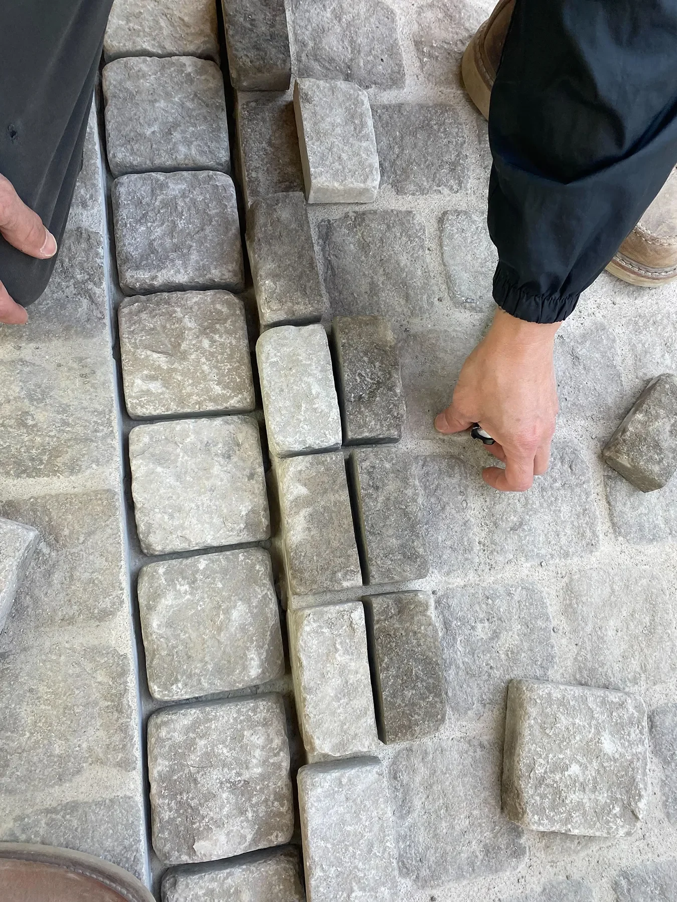 Setting the imported cobblestone by hand along a drain channel at By The Sea