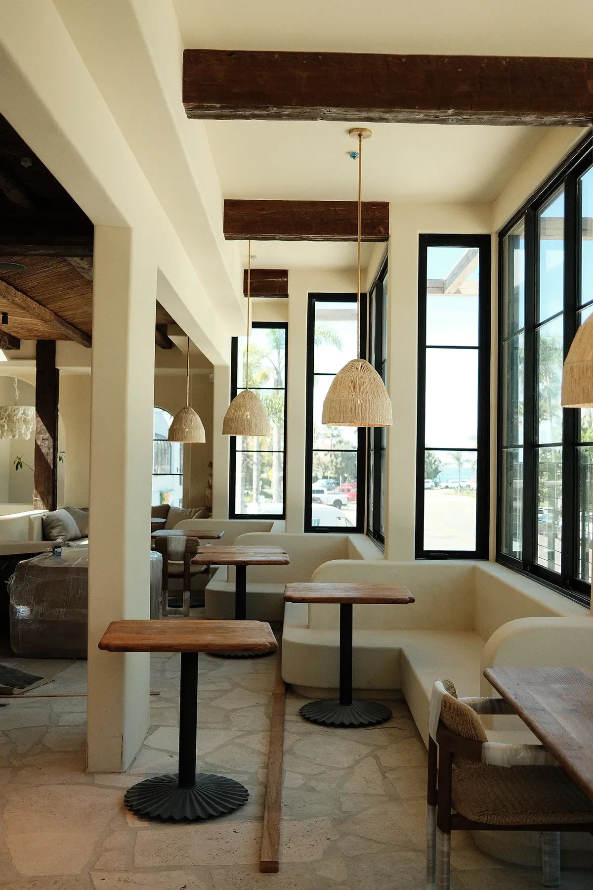 Oak wood tables and raffia dome pendants along the streetside windows at By The Sea in Coronado