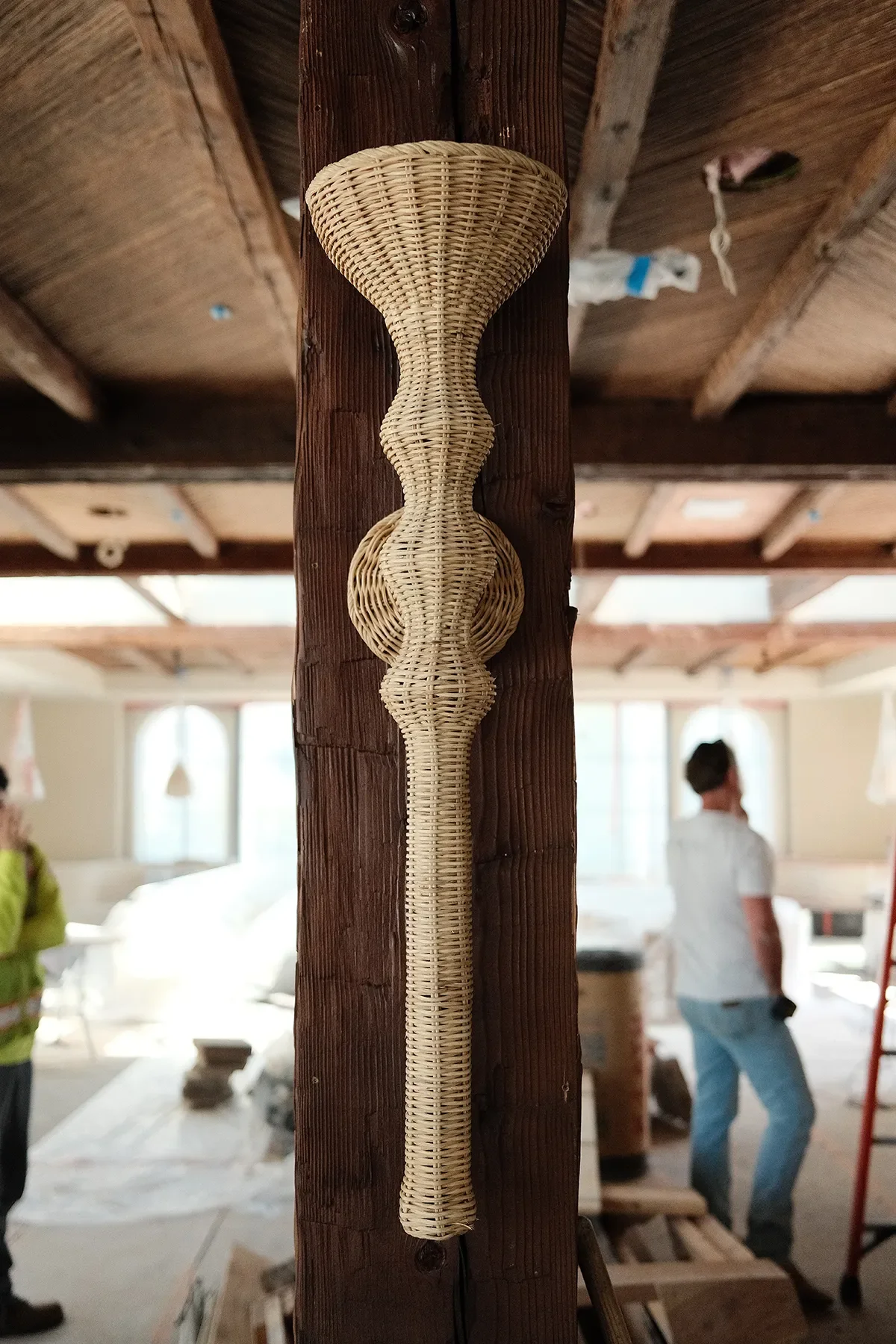 A sculptural woven sconce mounted on a reclaimed timber post at By The Sea