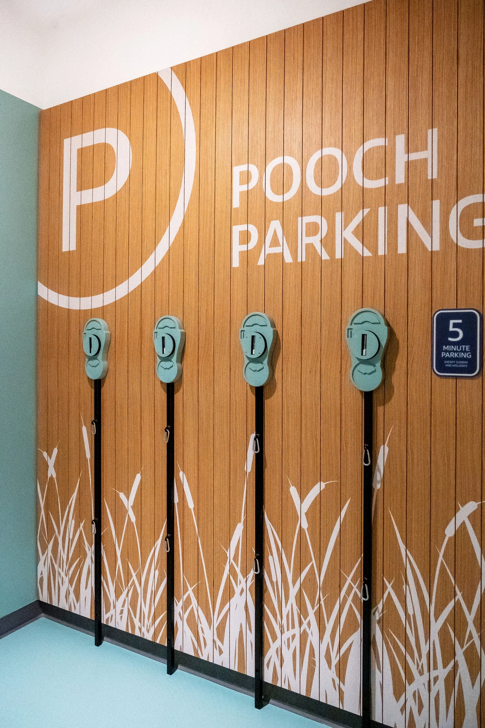 Pooch Parking signage with illustrated grasses, leash hooks and playful graphics in a commercial amenity space.