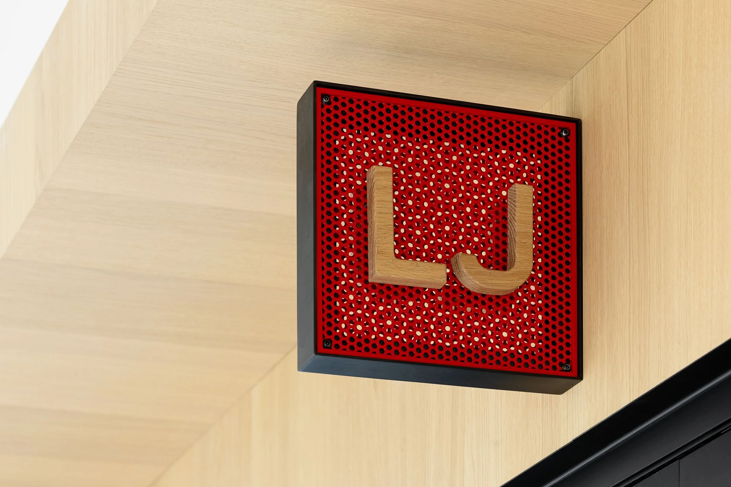 Custom signage made of red metal mesh mounted wall signage with wooden lettering.
