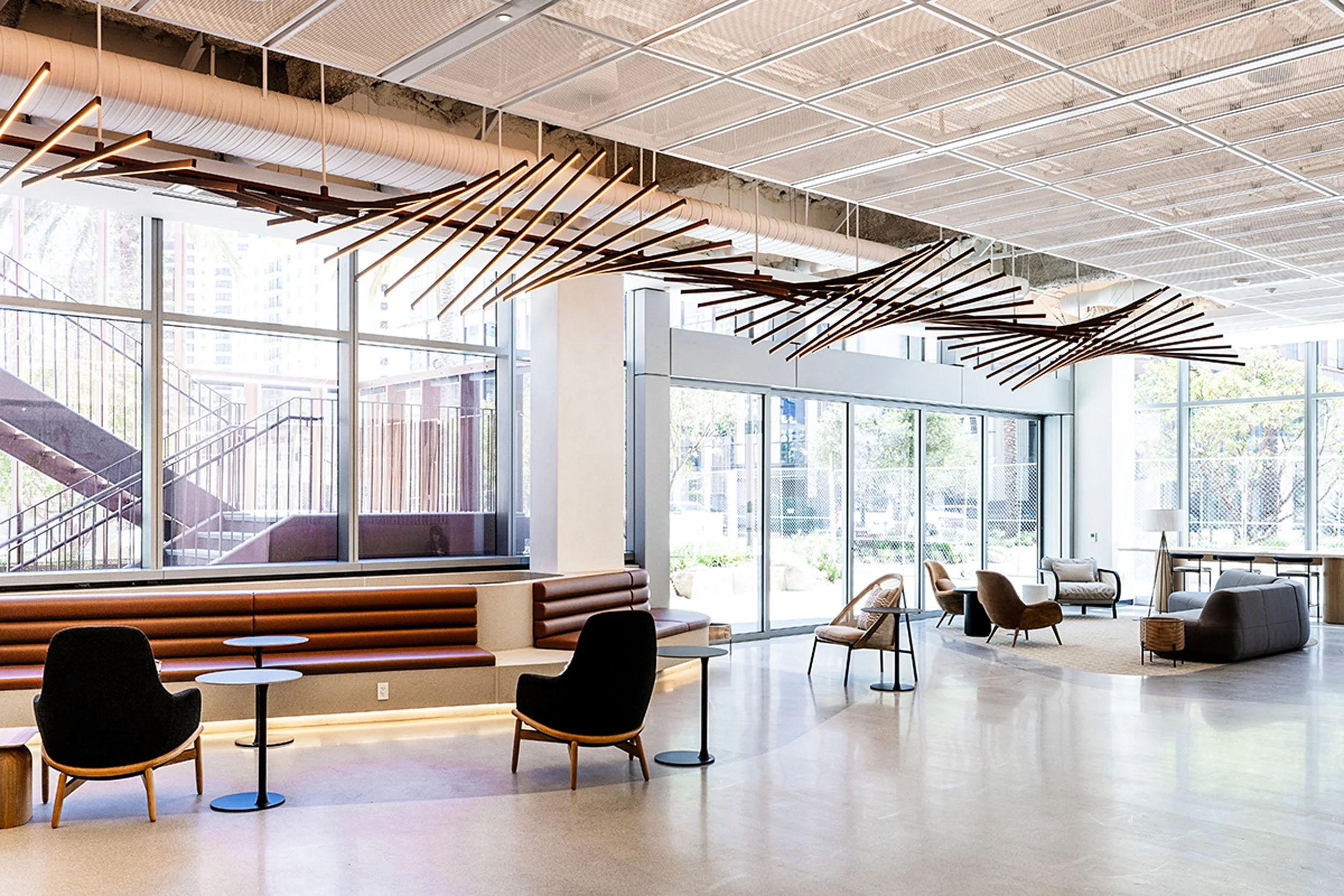 Bright workplace lobby with contemporary seating, and custom undulating light installation above.