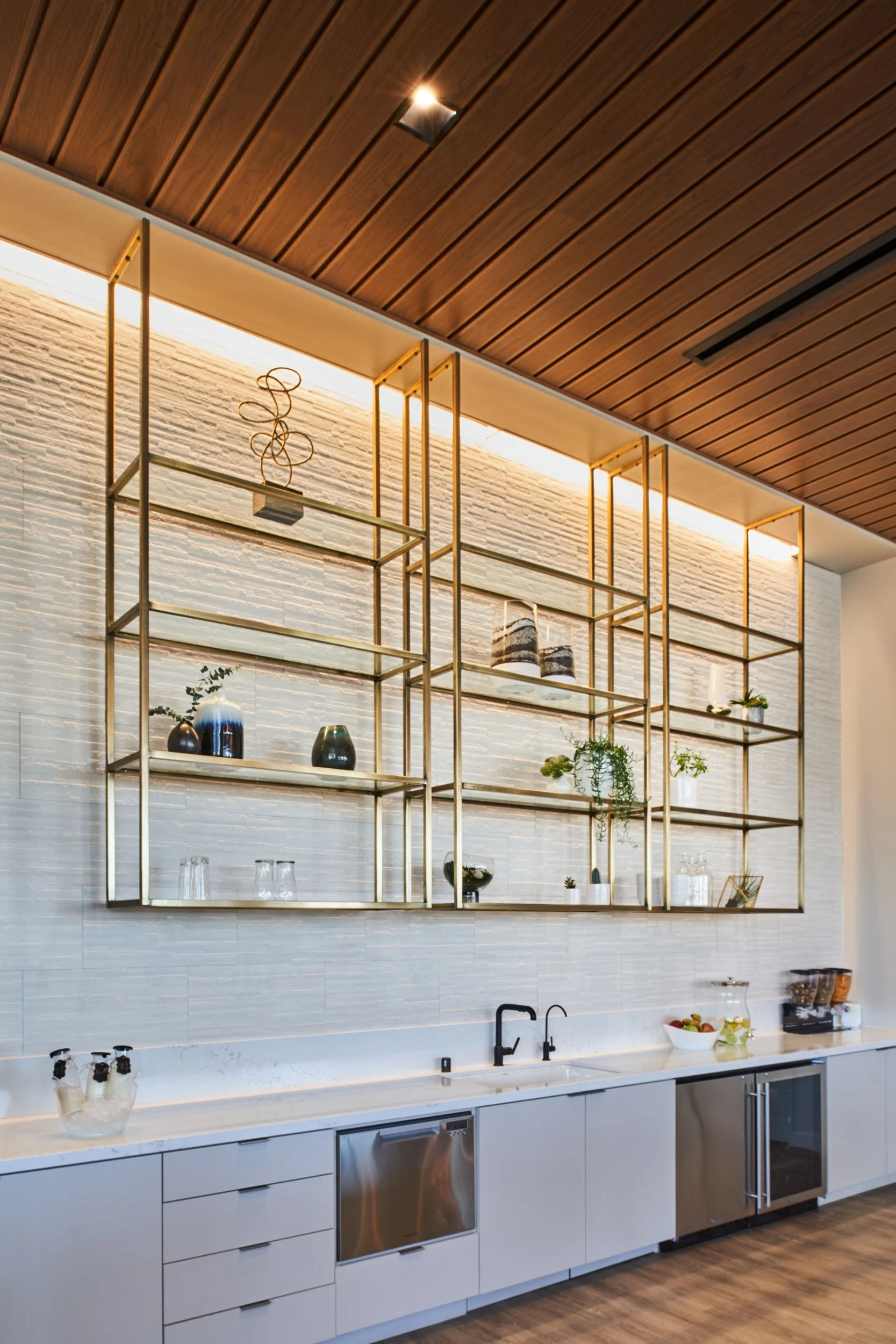 Custom open shelving and built-in cabinetry beneath a warm wood ceiling in a San Diego office space.
