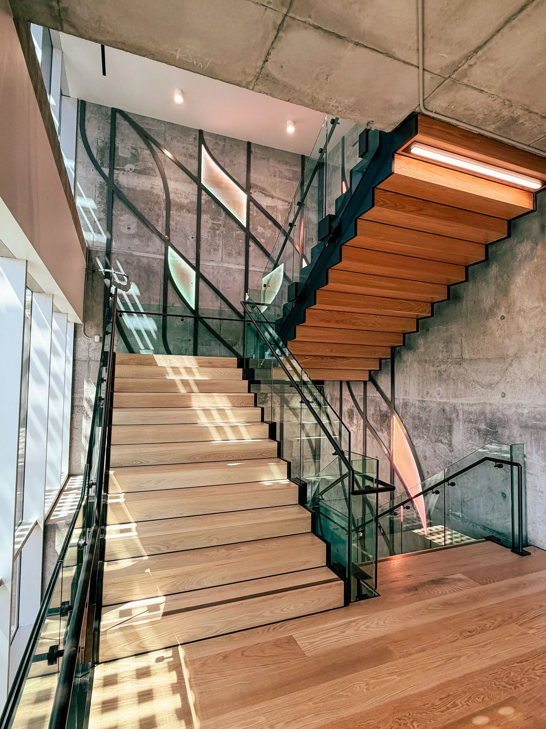 Wood stair treads, glass railings, and large-scale tree inspired metal artwork create a distinctive art installation.