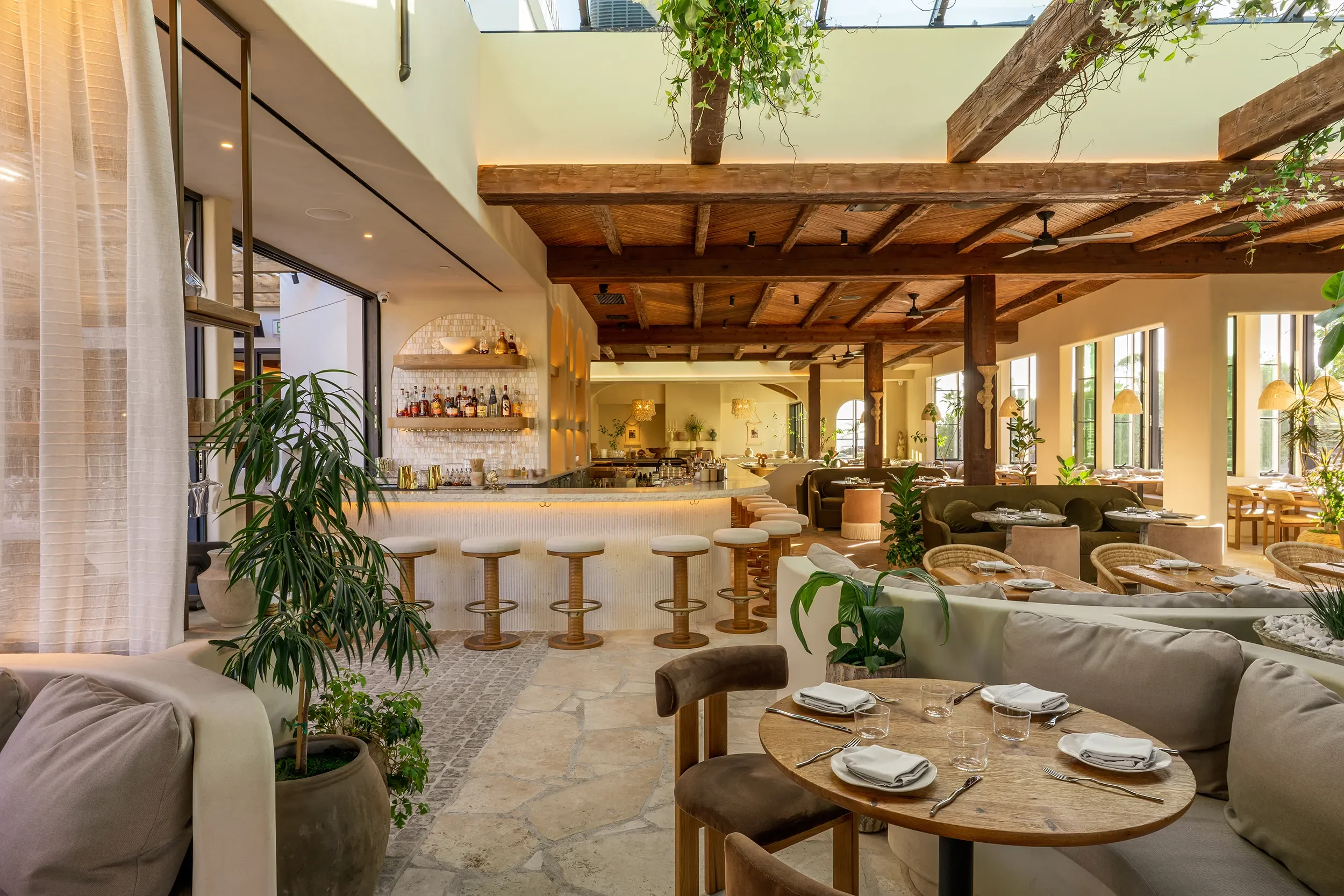 Round oak table set for two beside the stone bar and rattan stools at By The Sea in Coronado